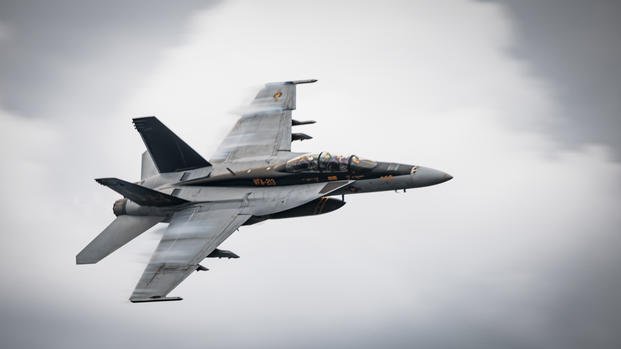 An F/A-18F Super Hornet, attached to Strike Fighter Squadron 213, piloted by Lt. Cmdr. Chris Kapuschansky with Gen. Sir Gwyn Jenkins, First Sea Lord and Chief of the Naval Staff, Royal Navy, embarked, flies over the world's largest aircraft carrier, USS Gerald R. Ford (CVN 78), Sept. 26, 2025.