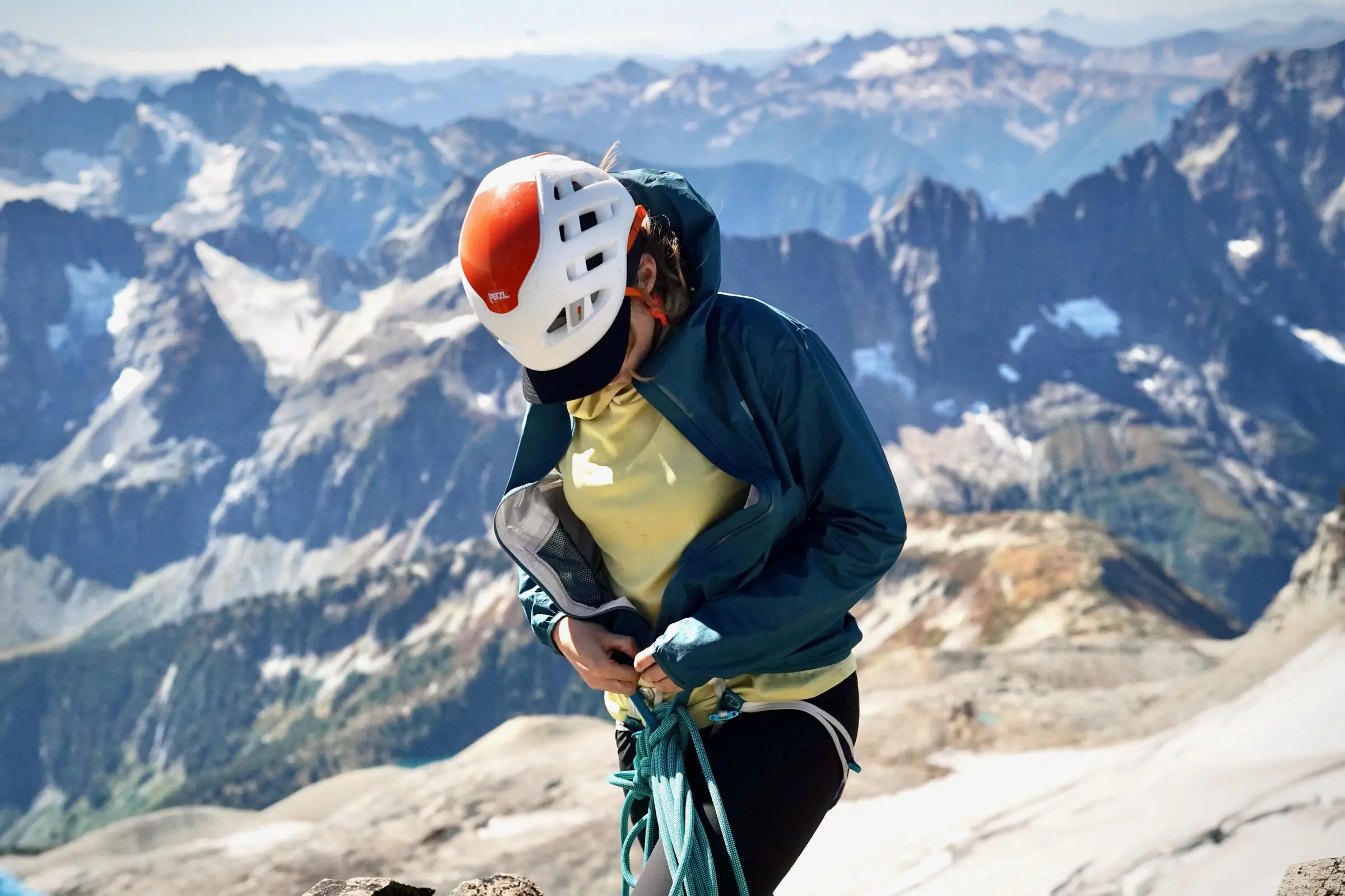 A woman wears a windbreaker jacket in front of a mountain range