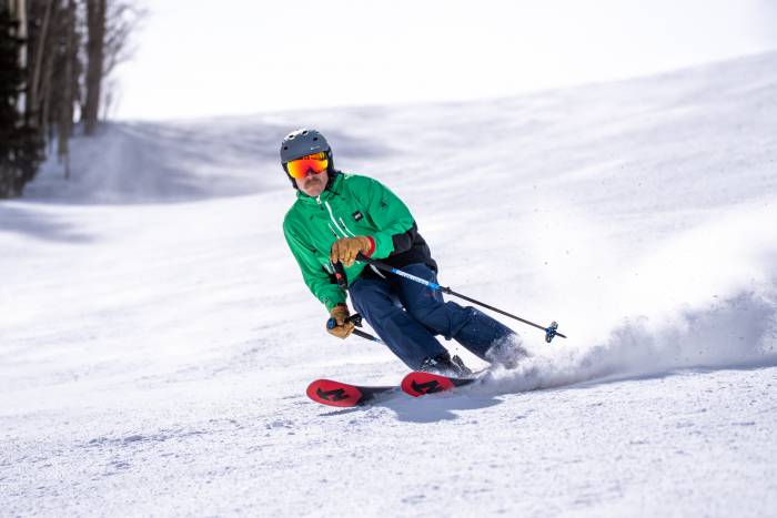 alpine skier descending groomer at resort