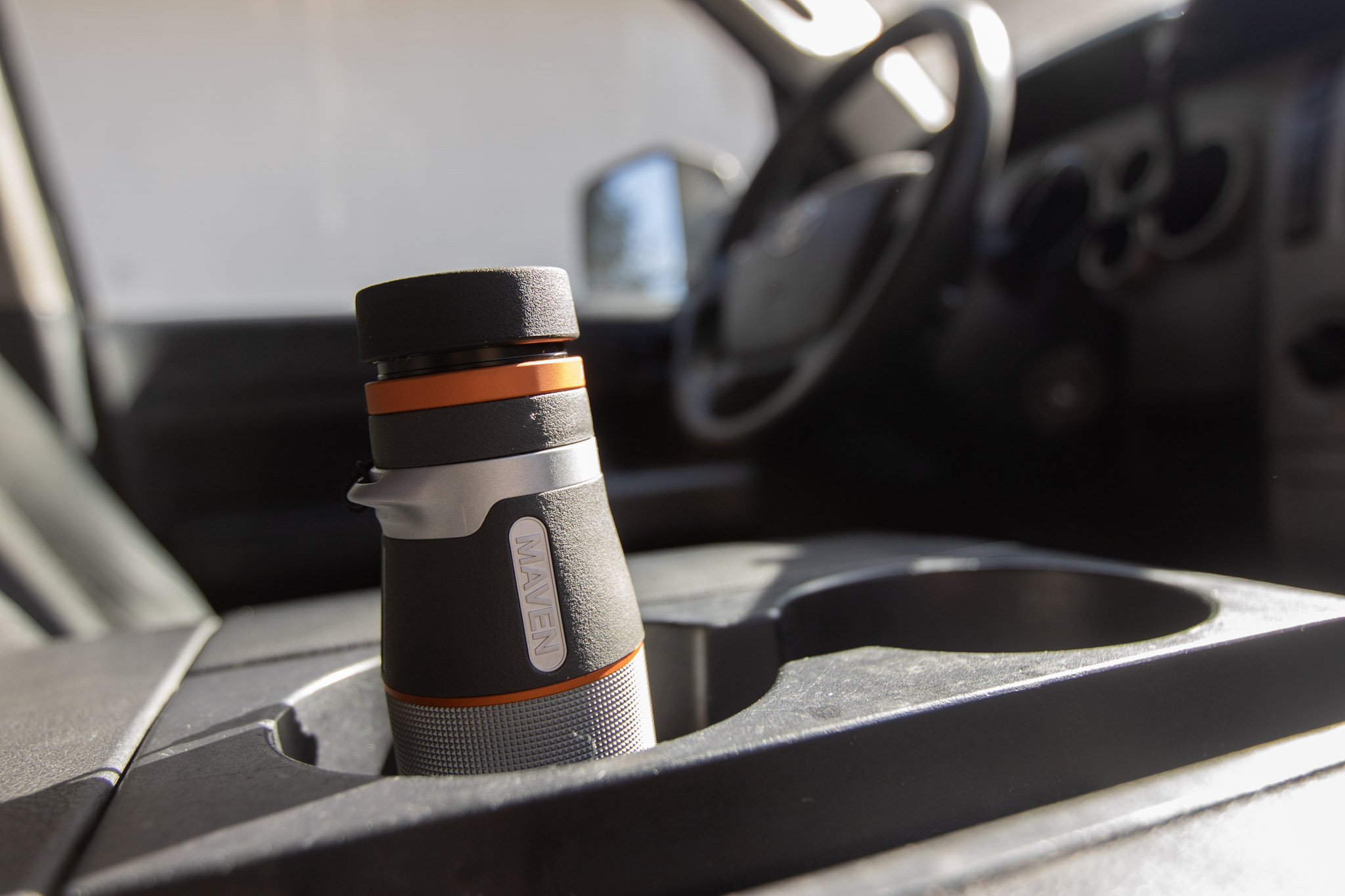 A monocular in a cupholder of a truck.