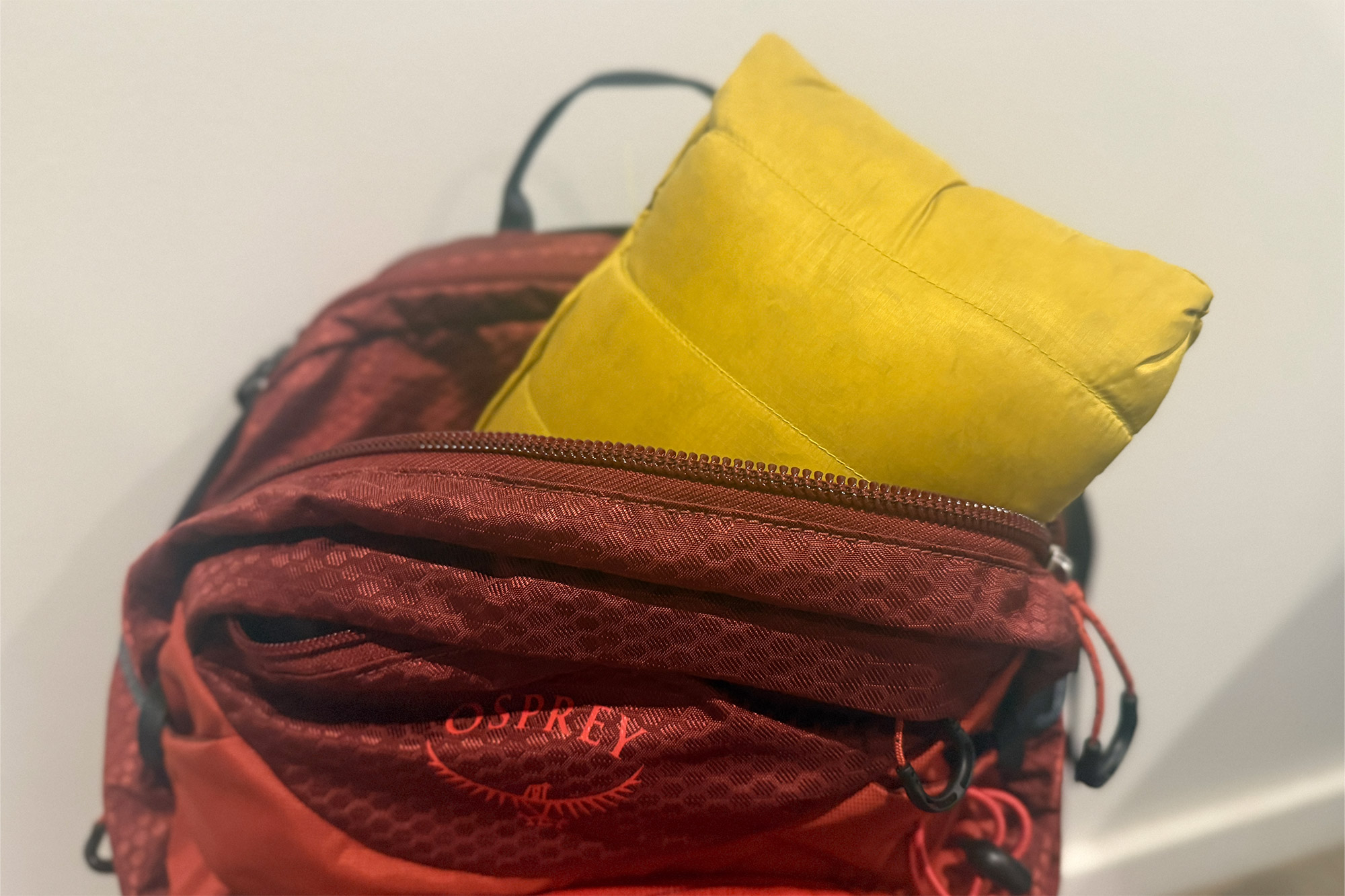 Yellow Rab Microlight Windstopper Hoody packed inside a red Osprey backpack