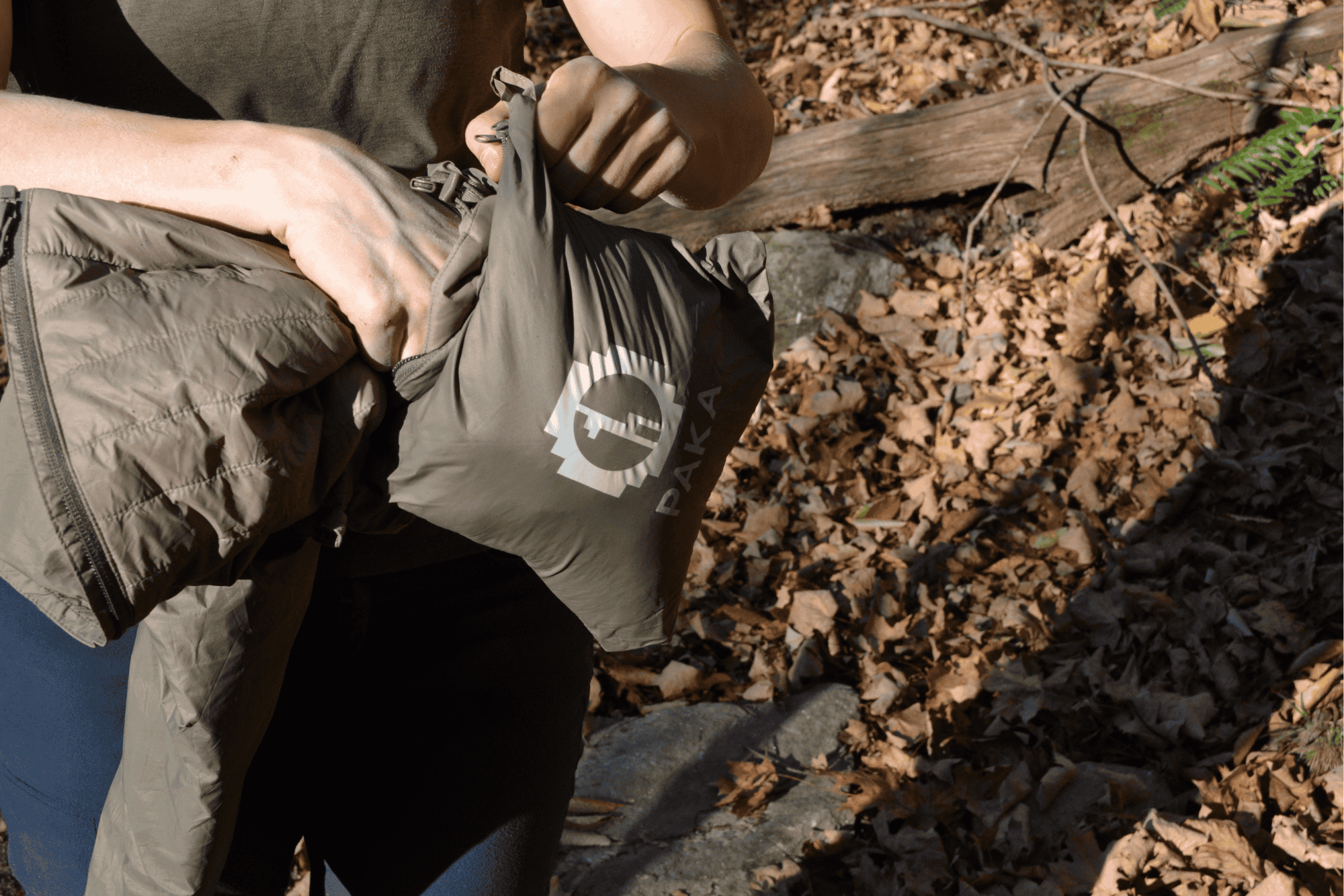 person stuffs jacket into stuff sack