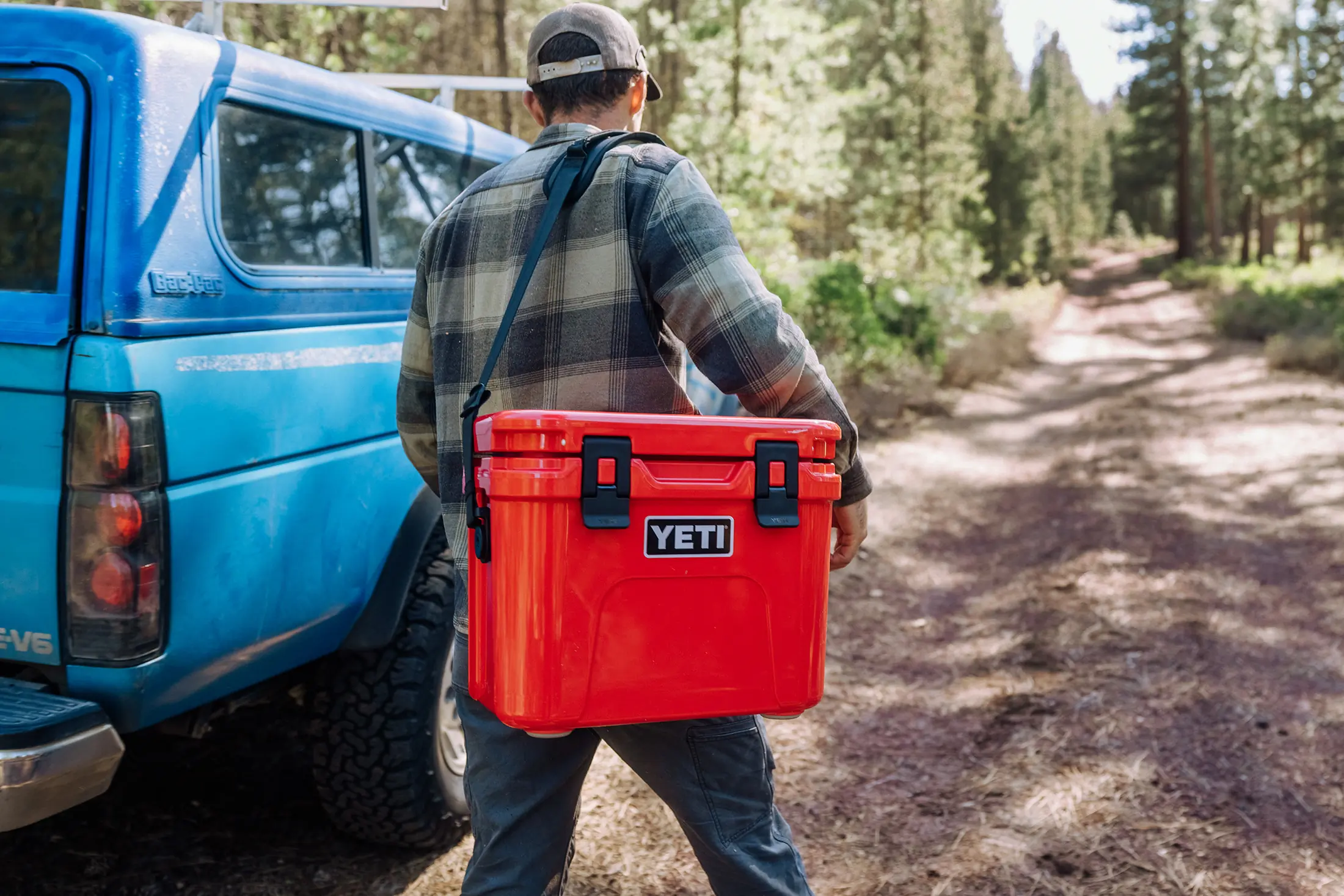 yeti roadie 15 hard cooler man carrying by truck in woods