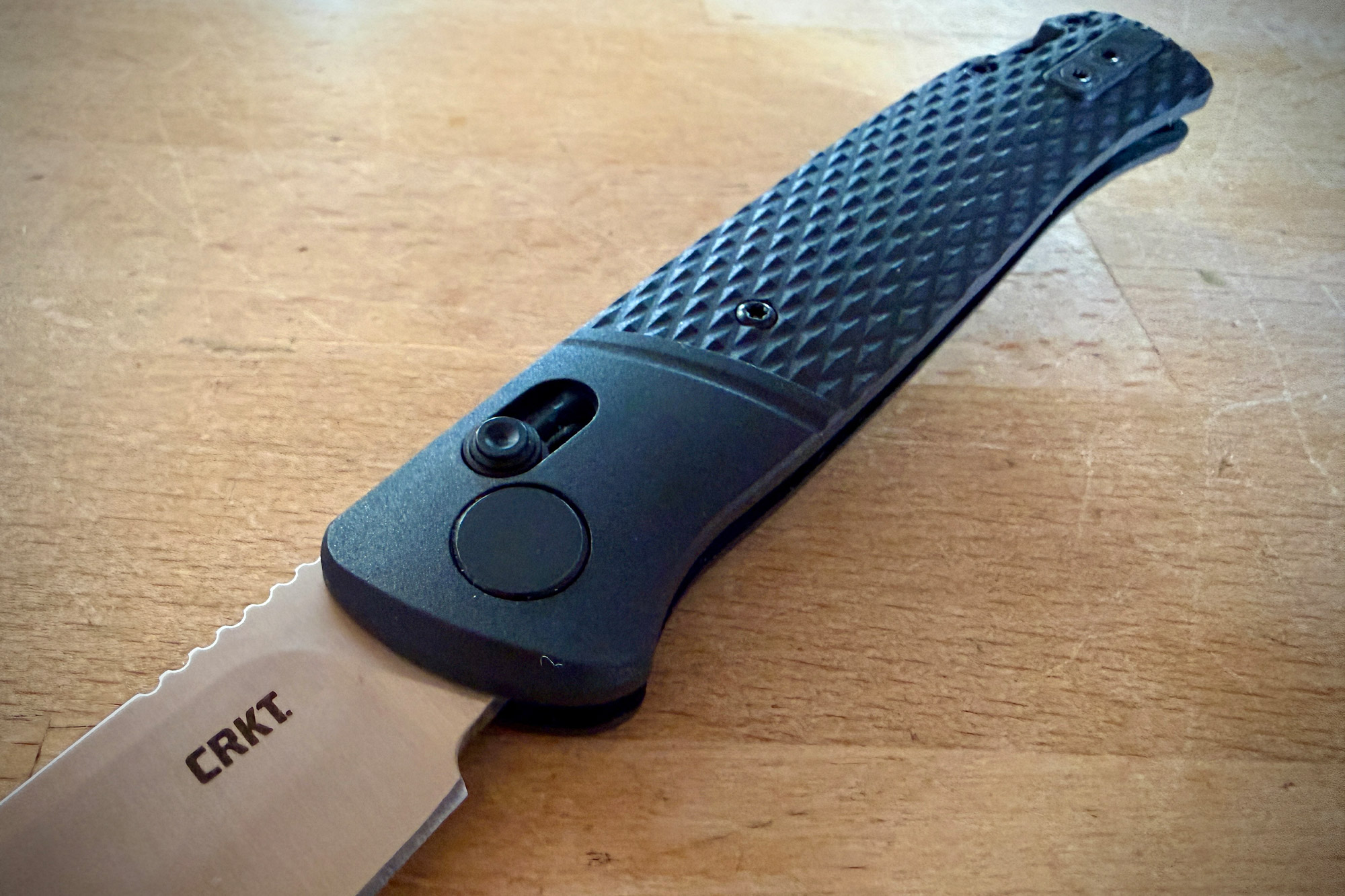 The CRKT knife open on a wooden surface with the blade and handle fully visible