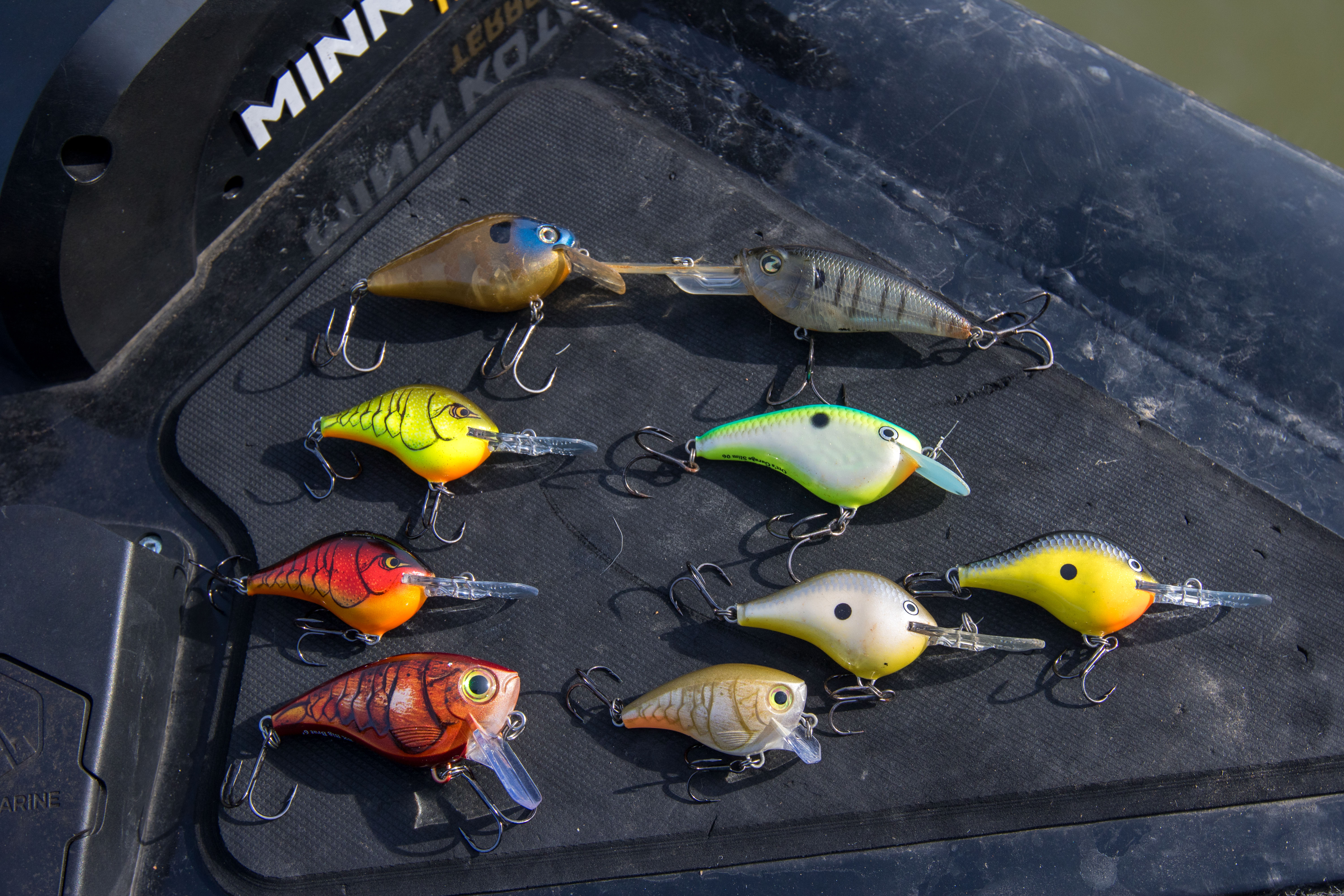 A selection of different colored crankbaits on the bow of a boat.