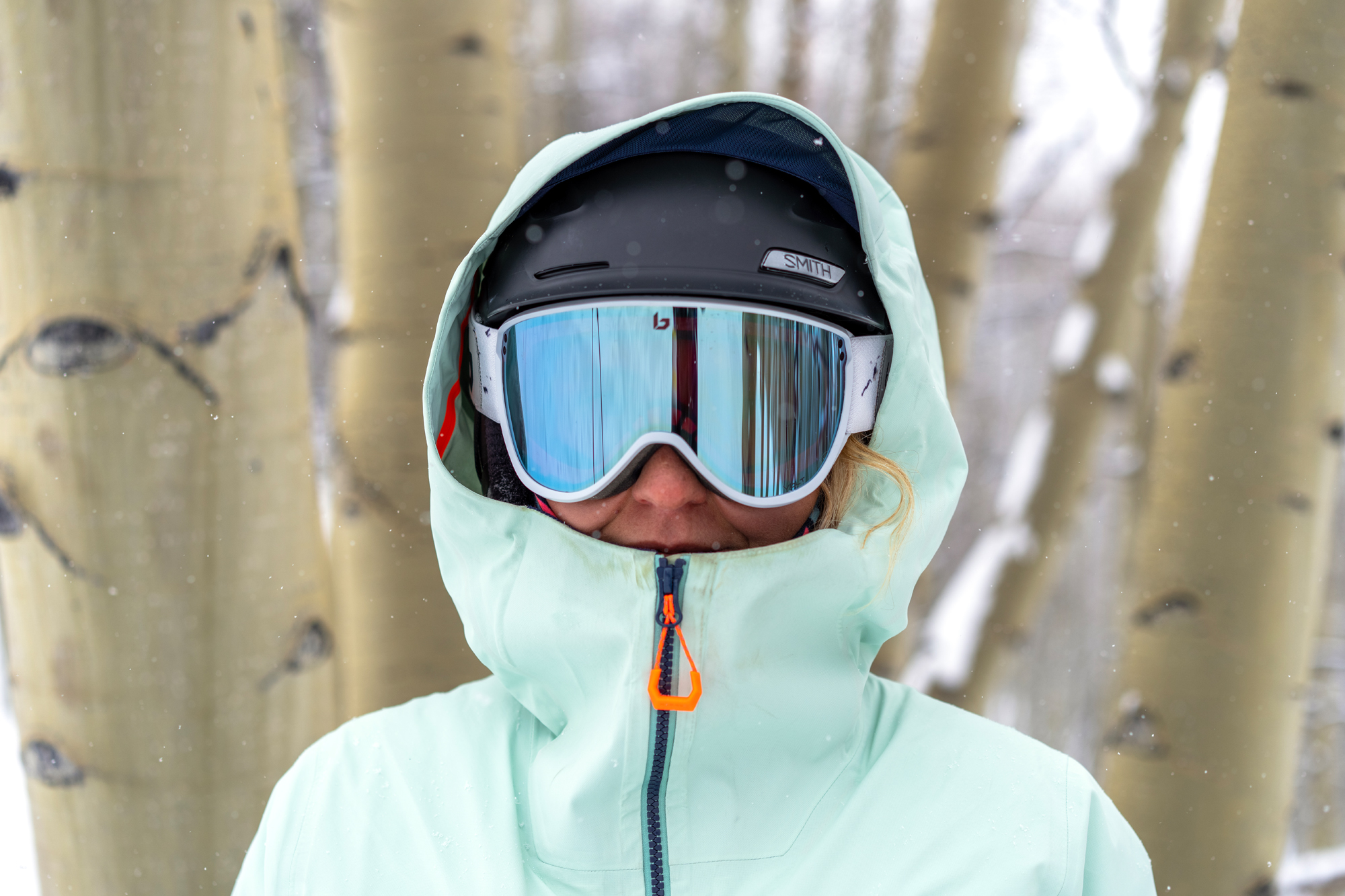 woman testing bright teal ski jacket and goggles 