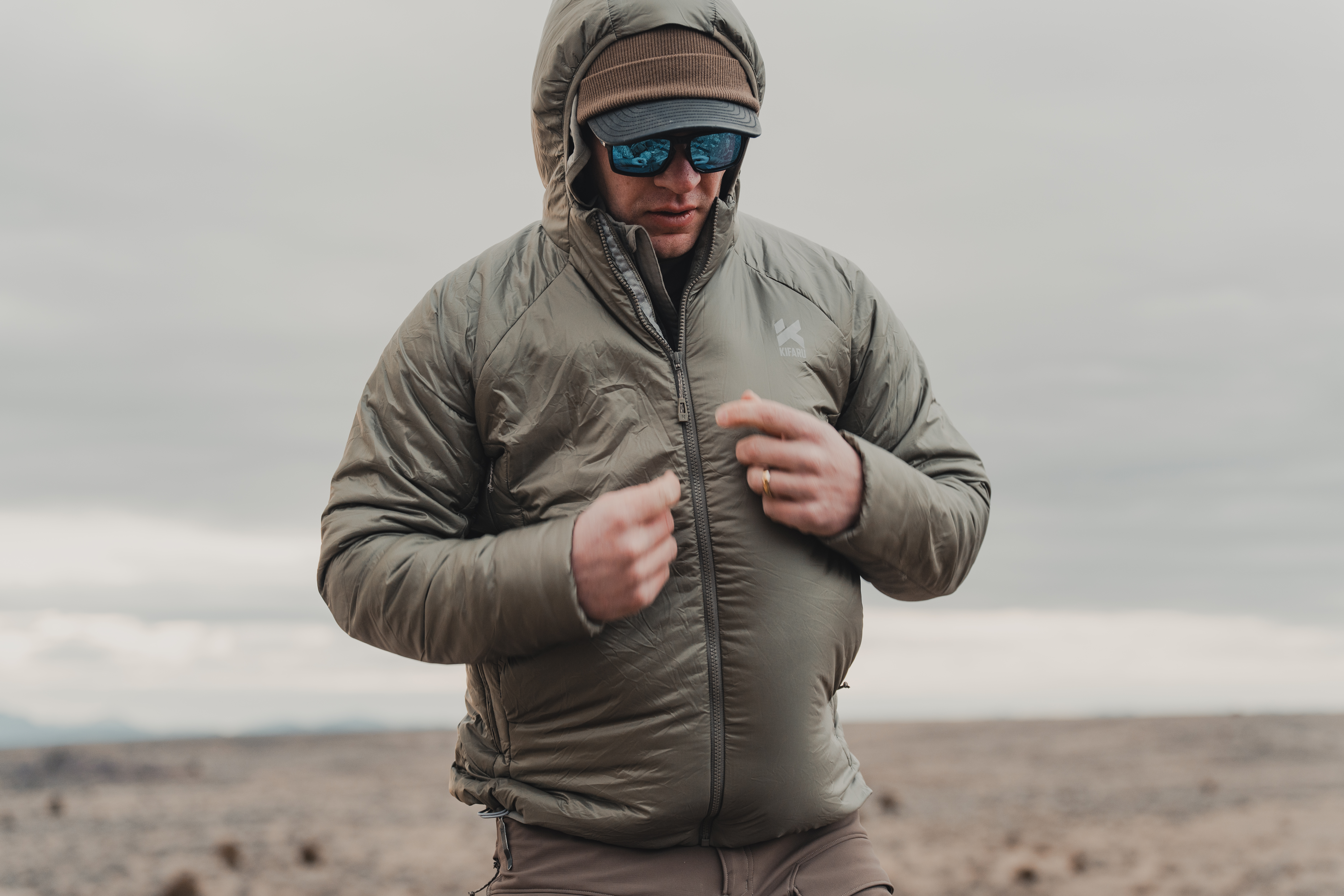 A hunter in a cold winter environment zipping up the Kidaru Pointe Synthetic Puffy.