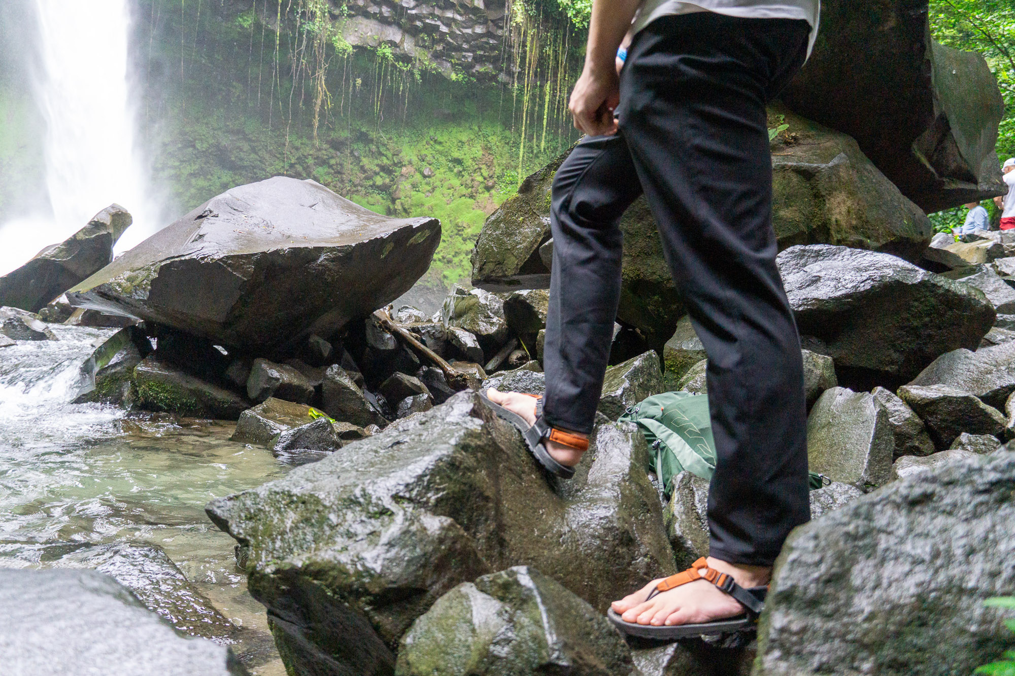 the author wearing the unbound merino travel pants in the costa rica jungle beside a waterfall