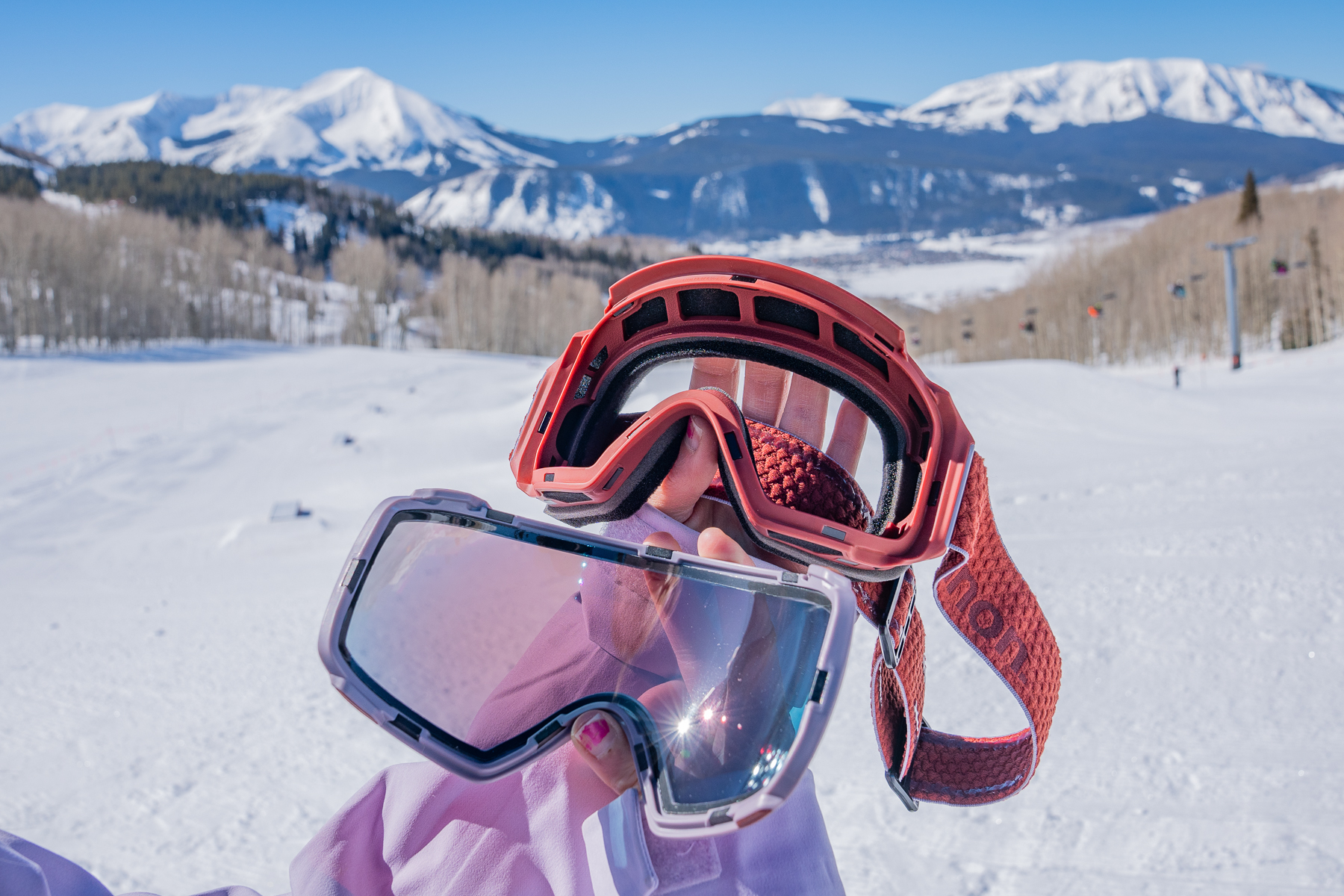 a goggle lens and frame with mountains in the backdrop
