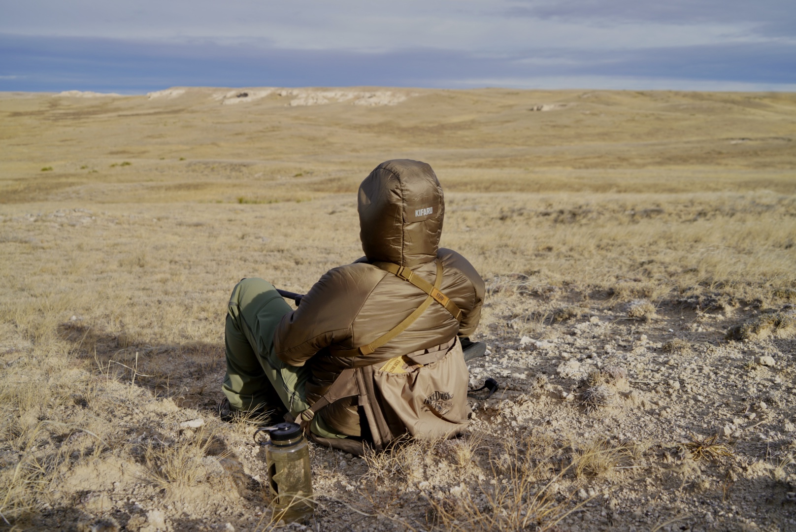 A hunter bundled up looking at a plains landscape.