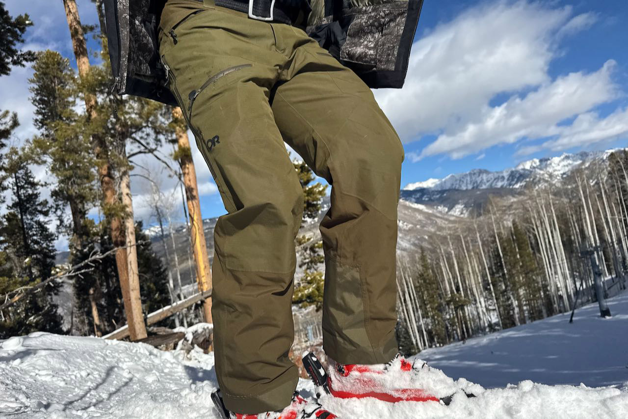 Outdoor Research ski pants worn in deep snow with mountains in the background