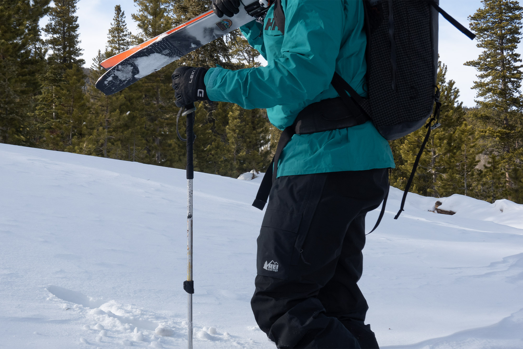 A skier moves uphill in deep snow while wearing REI Co-op First Chair ski bibs