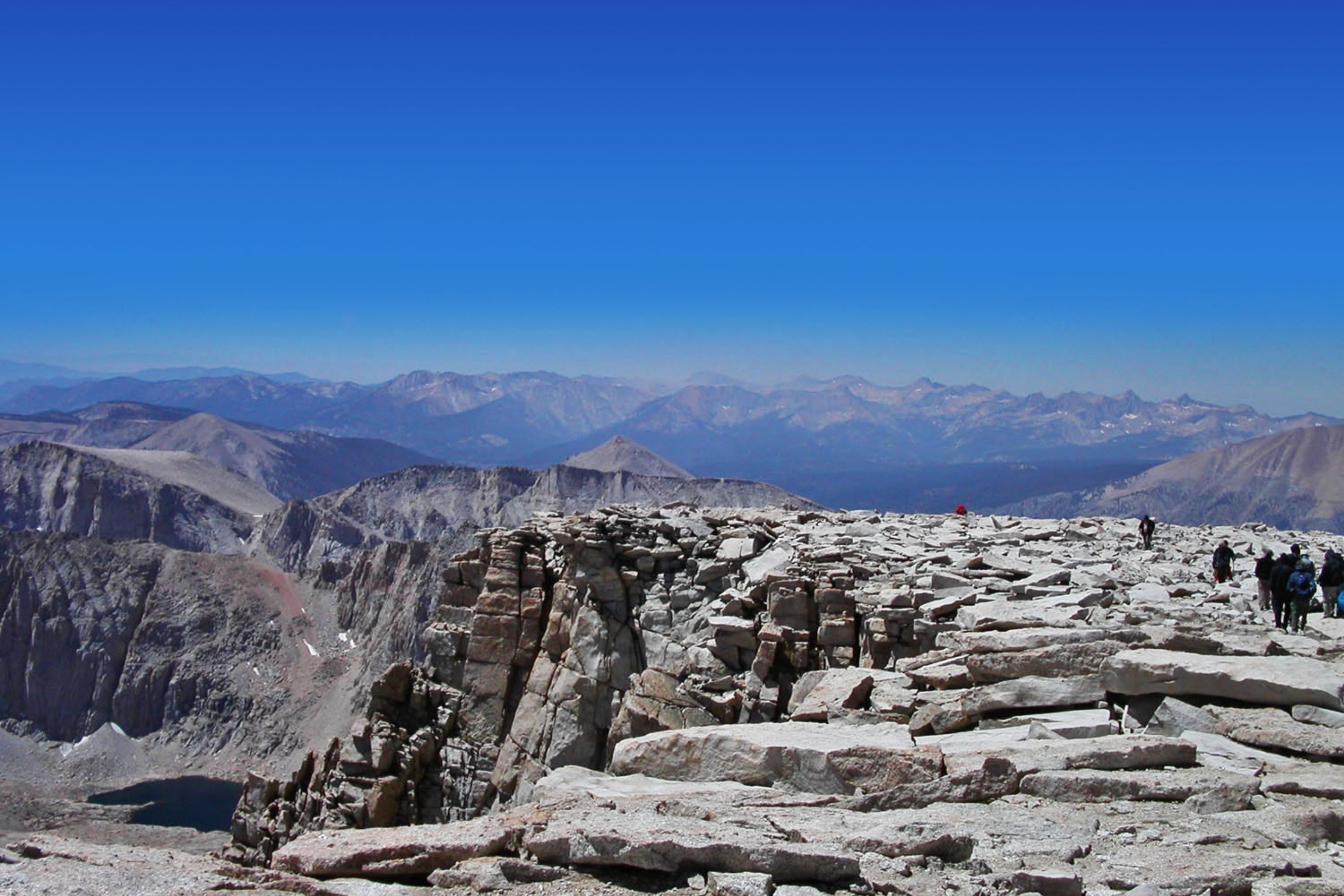 hikers on top of mountain with more mountains in the distance