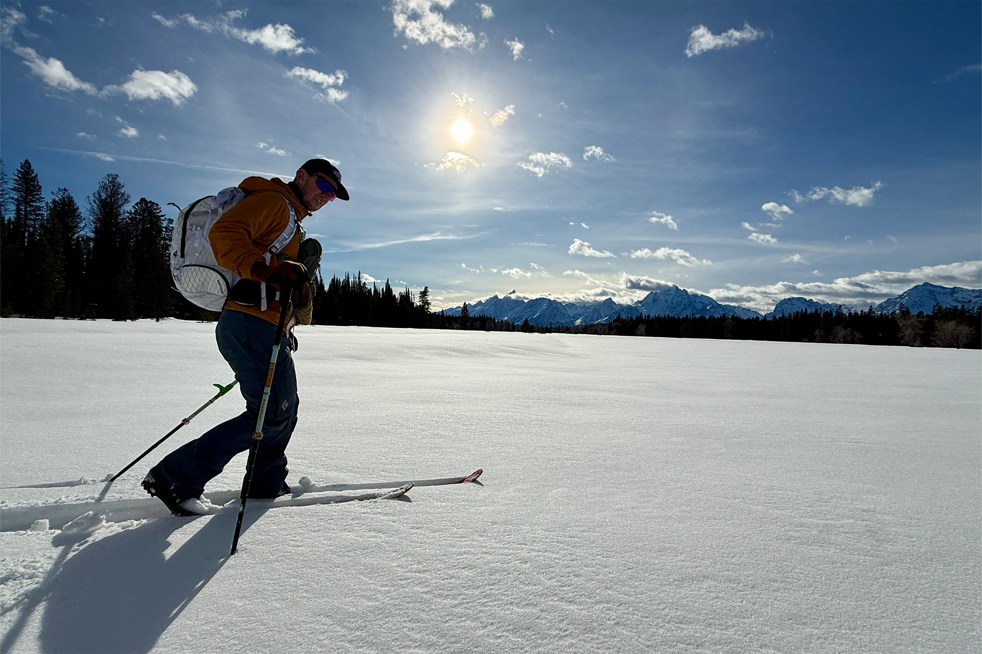 A skier travels across a wide snowy meadow on the XP 105 Positrack skis under bright sun