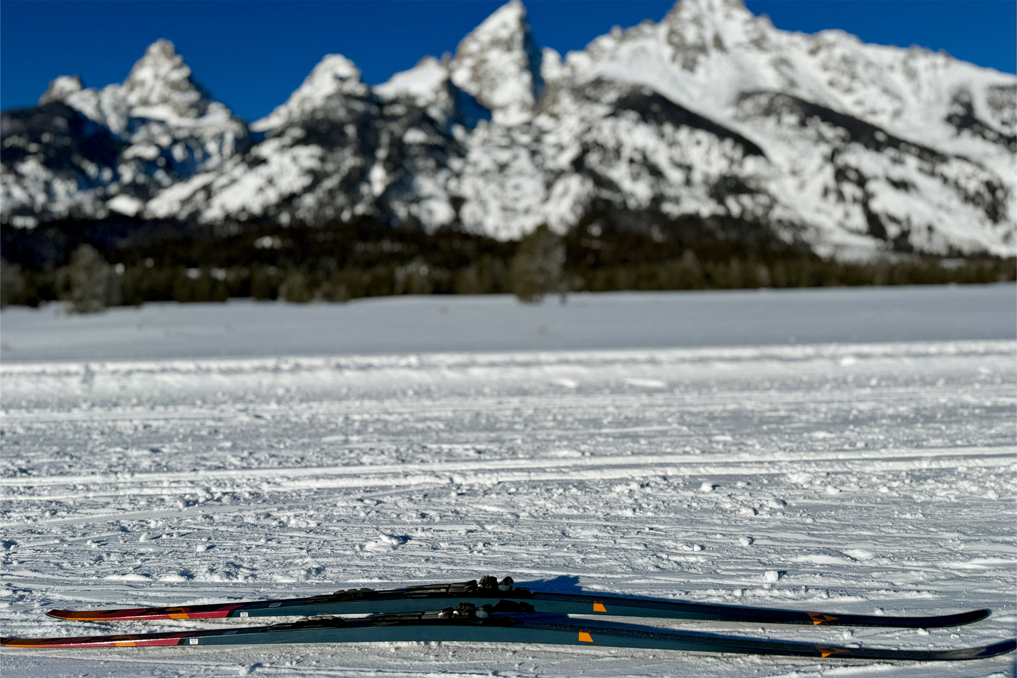 The Aeroguide 85s lie flat on snow with a blurred mountain range in the background