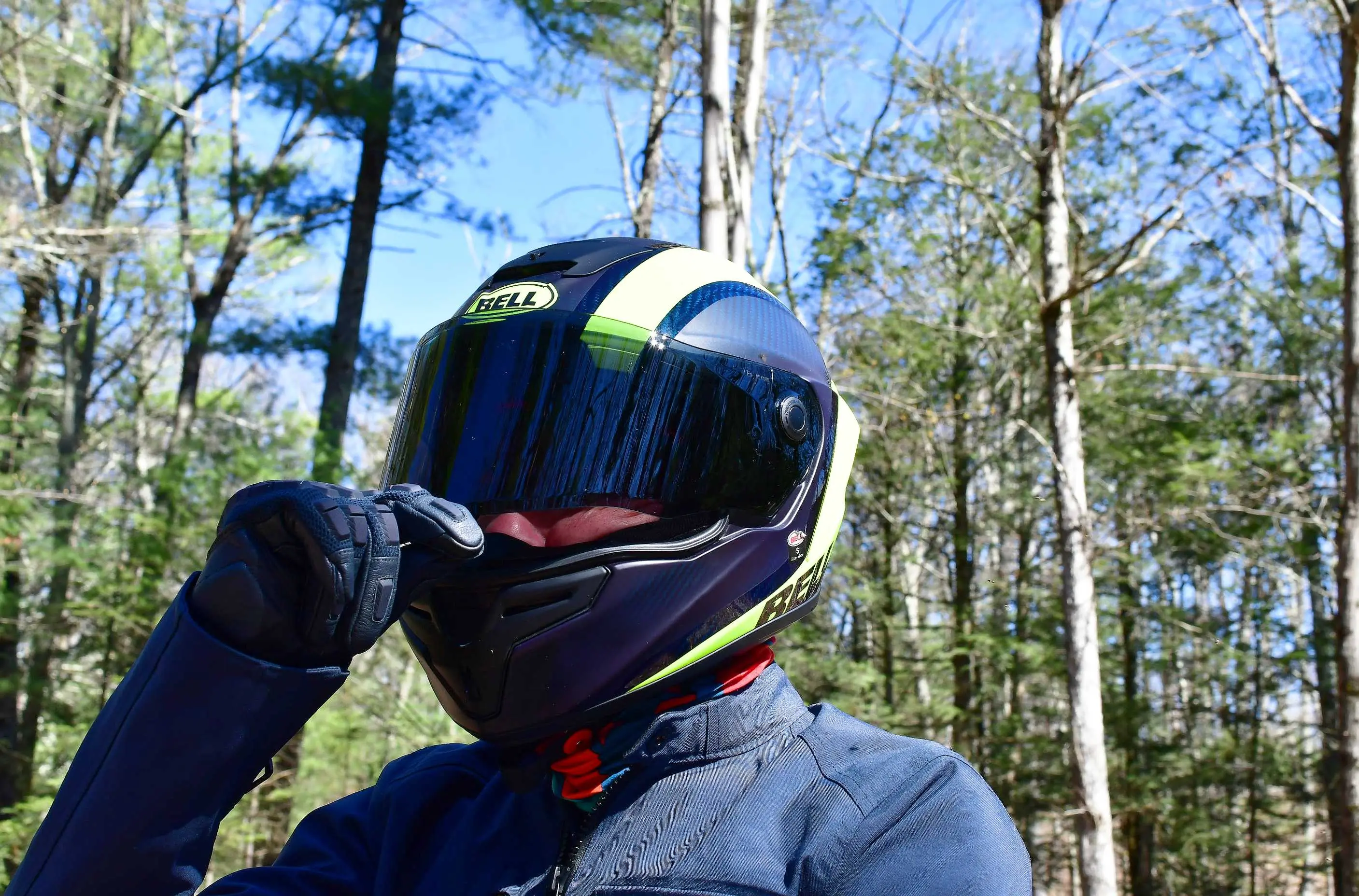 motorcycle rider pulling down visor on helmet in woods 