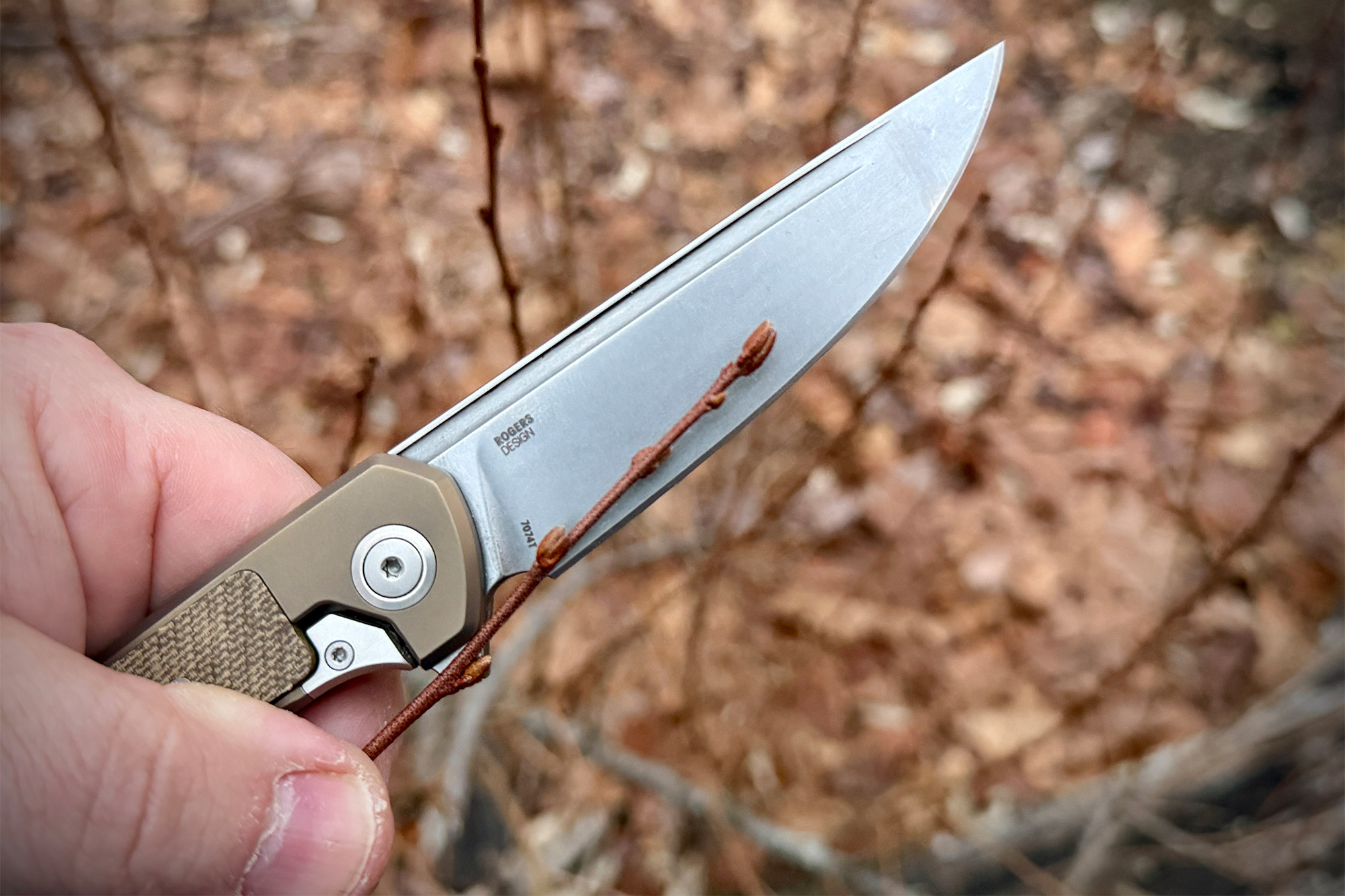 CRKT Q Frame Lock knife cutting a small branch outdoors showing blade edge in use