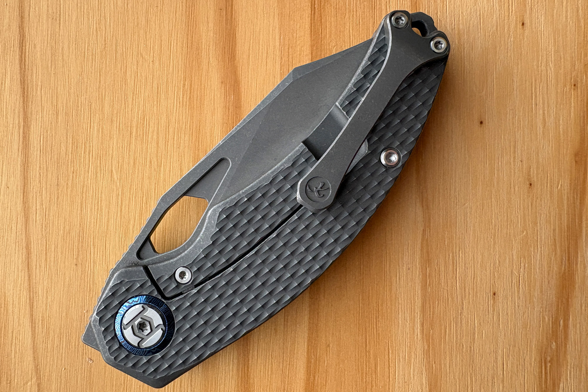 Closed Compadre knife showing the pocket clip side on a wooden surface