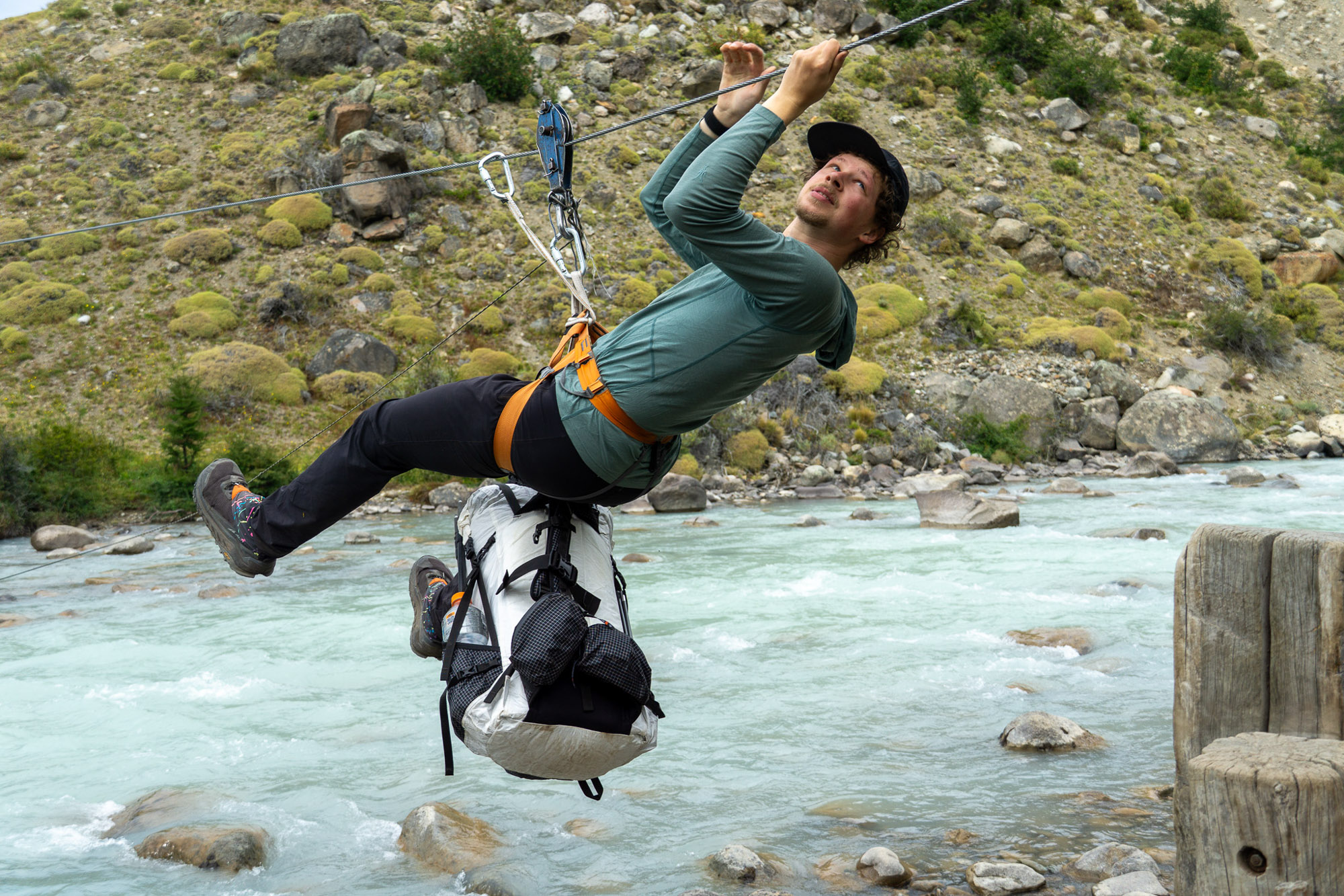 a gearjunkie tester crossing a river in patagonia via tyrolean traverse with a hyperlite mountain gear southwest pack below him