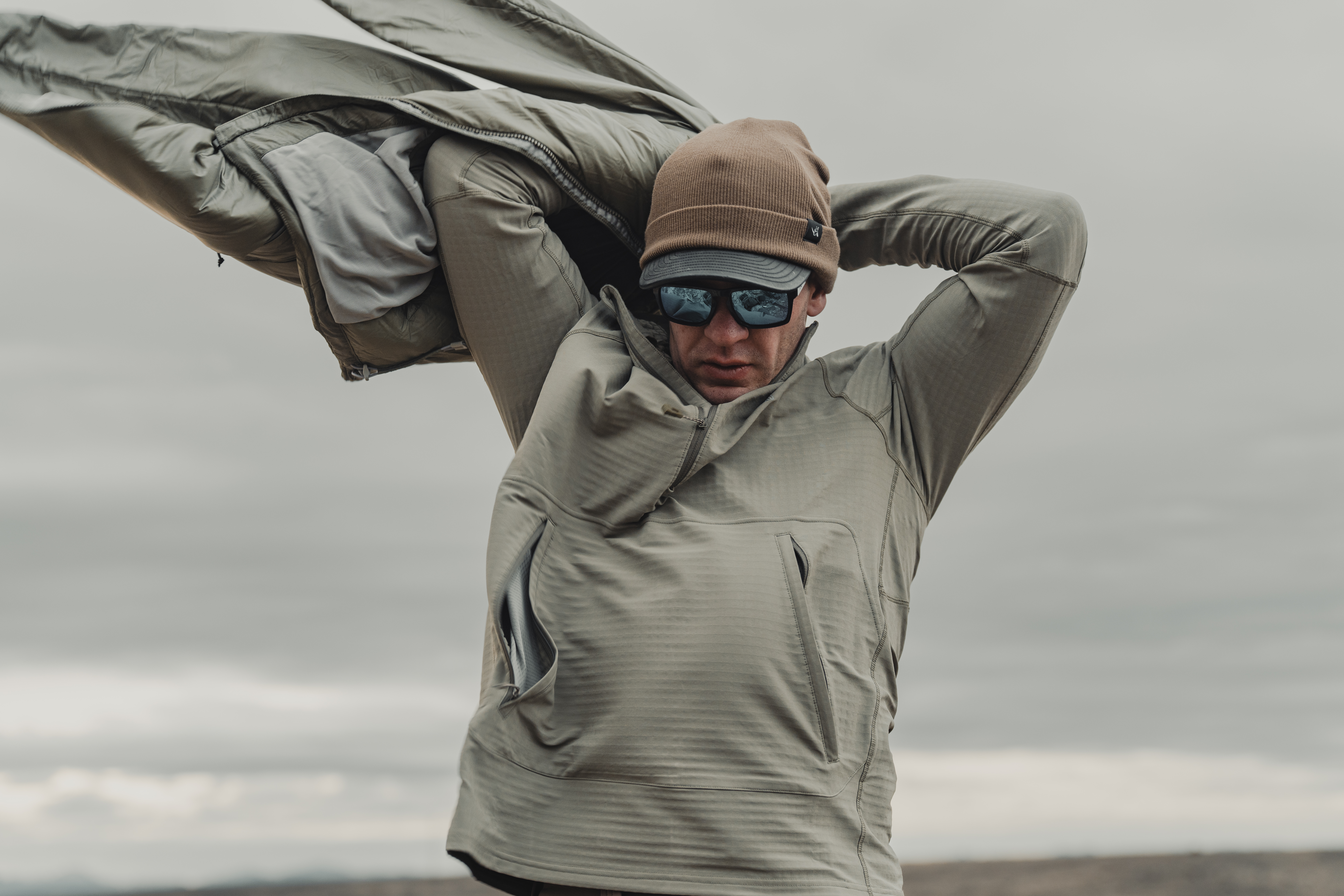 A hunter putting a puffy jacket over the Kifaru Crosslayer hoodie.