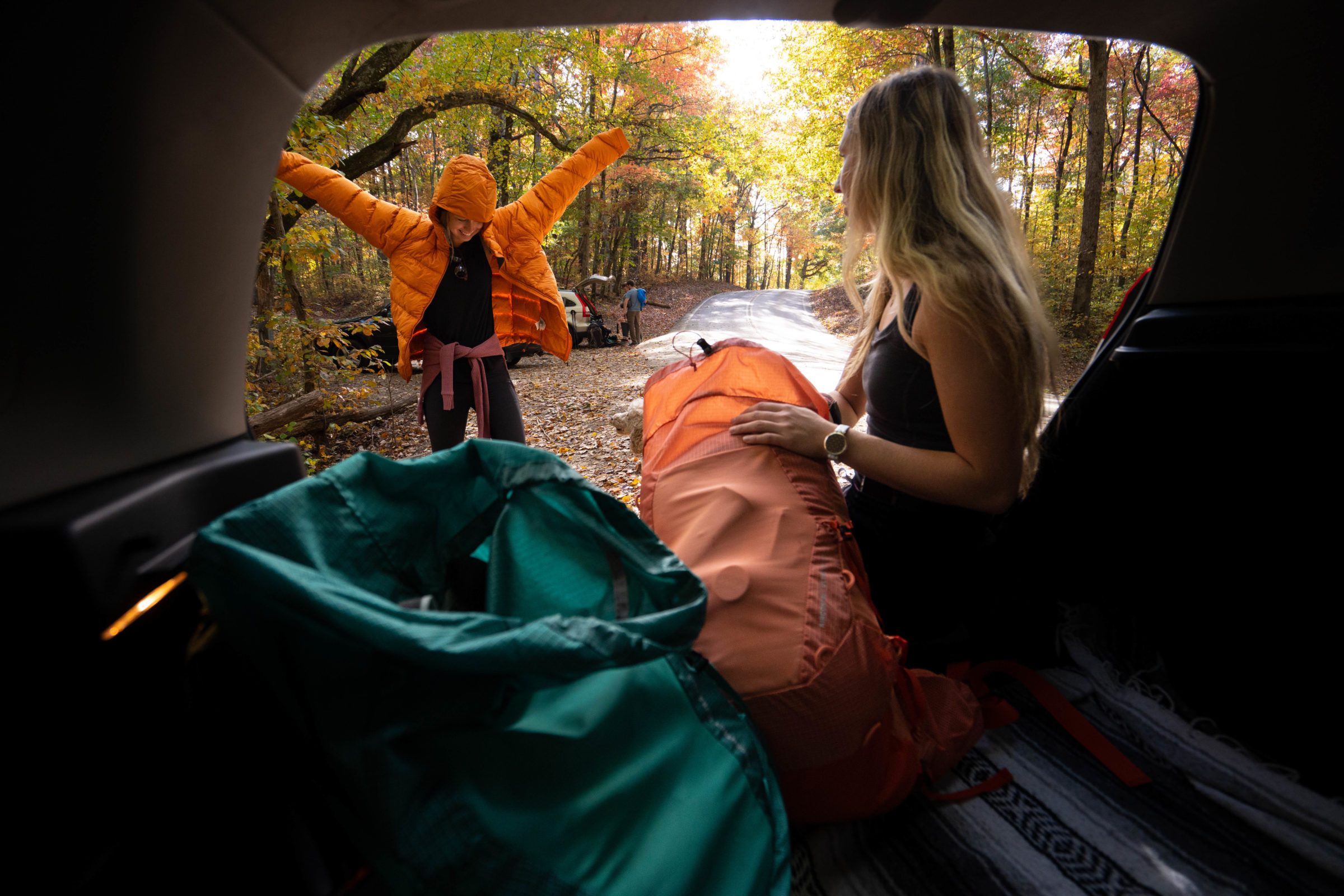 two backpackers get their bags ready in the back of a car at a trailhead in the southeast