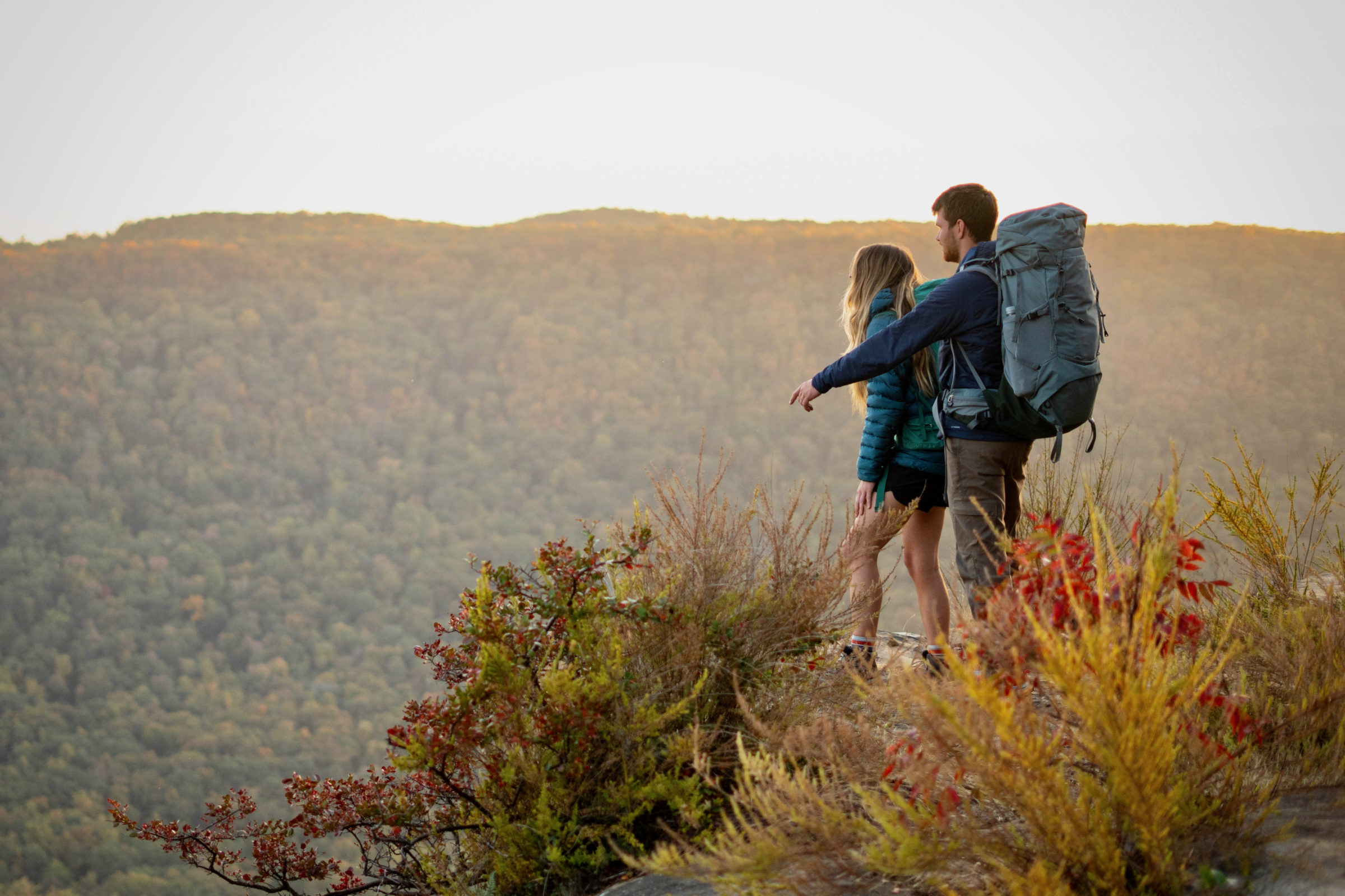 Two hikers overlook a view in the southeast while wearing backpacking packs