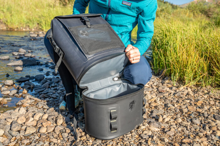 person opening the base of a large backpack cooler