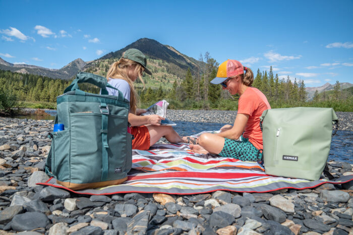 two women sitting by a river