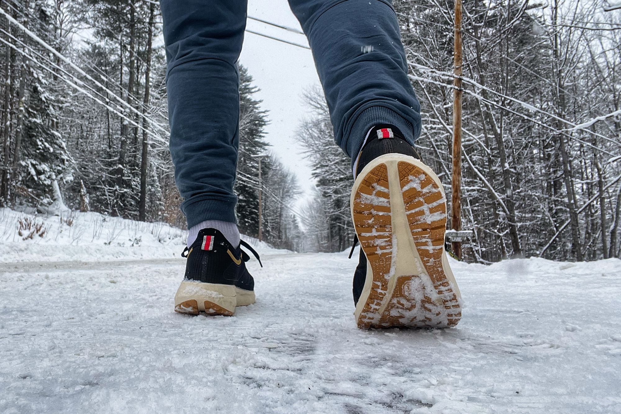 Bottom of a Tracksmith Eliot NDO shoe visible as a runner walks on a snowy road