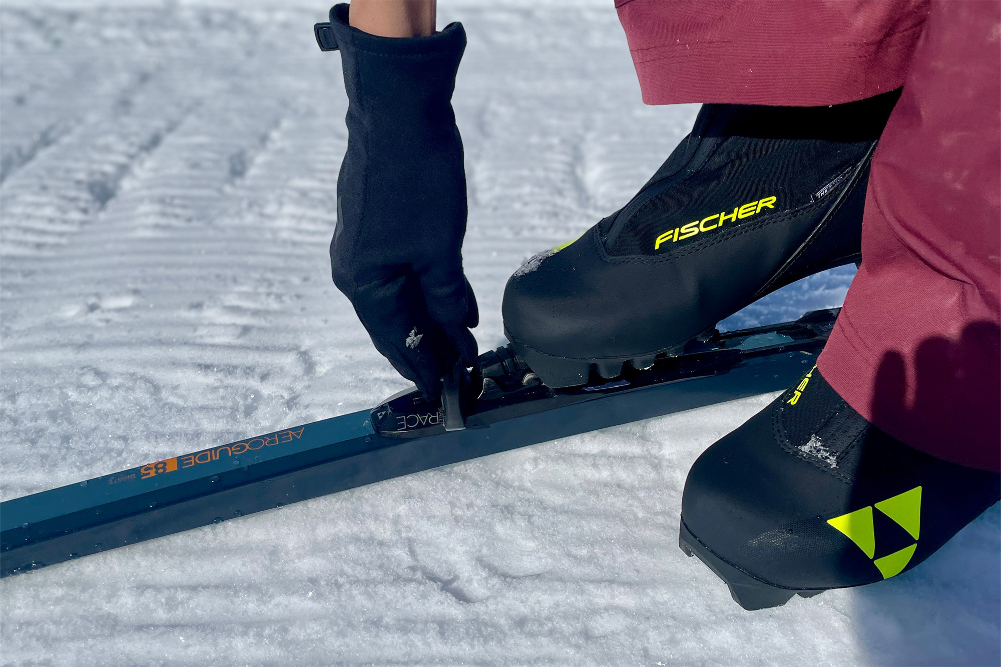A skier clips into the Fischer Aeroguide 85 Skate binding on packed snow