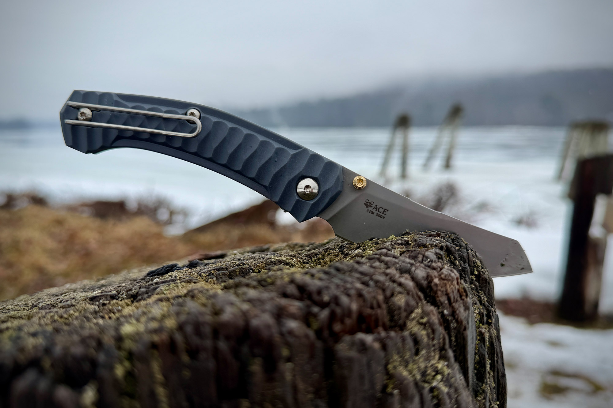 The ACE Iona Sailor knife balanced on a weathered wooden post near a misty waterfront
