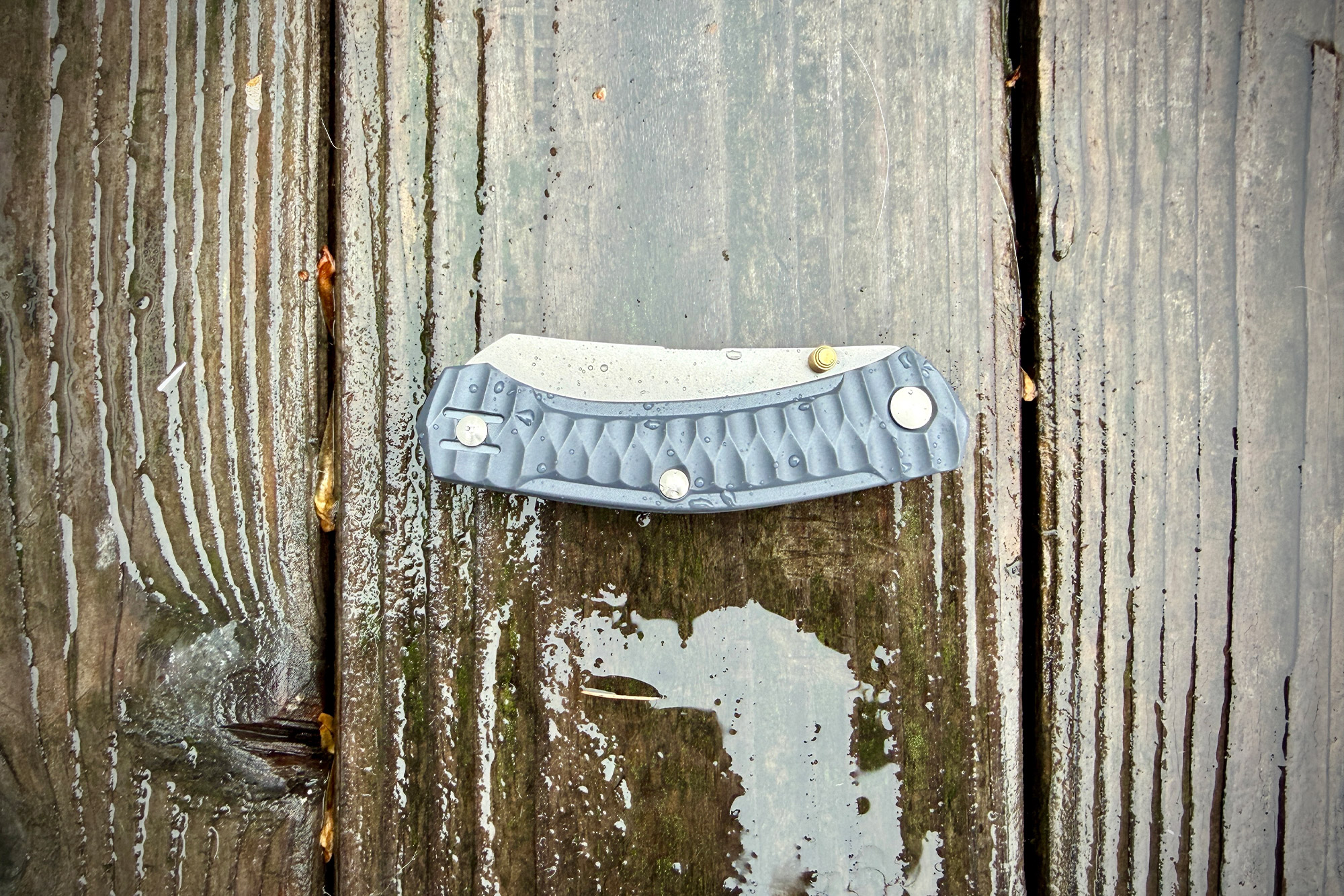 The GiantMouse ACE Iona Sailor closed and resting on wet wooden boards with water droplets