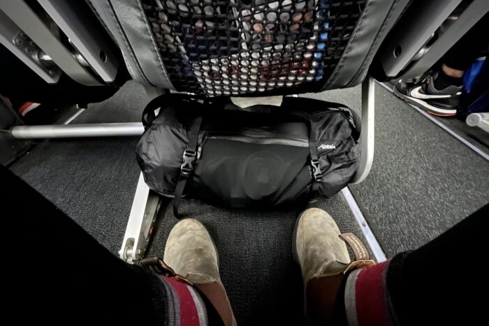 Duffel bags under seat in plane as carry-on.