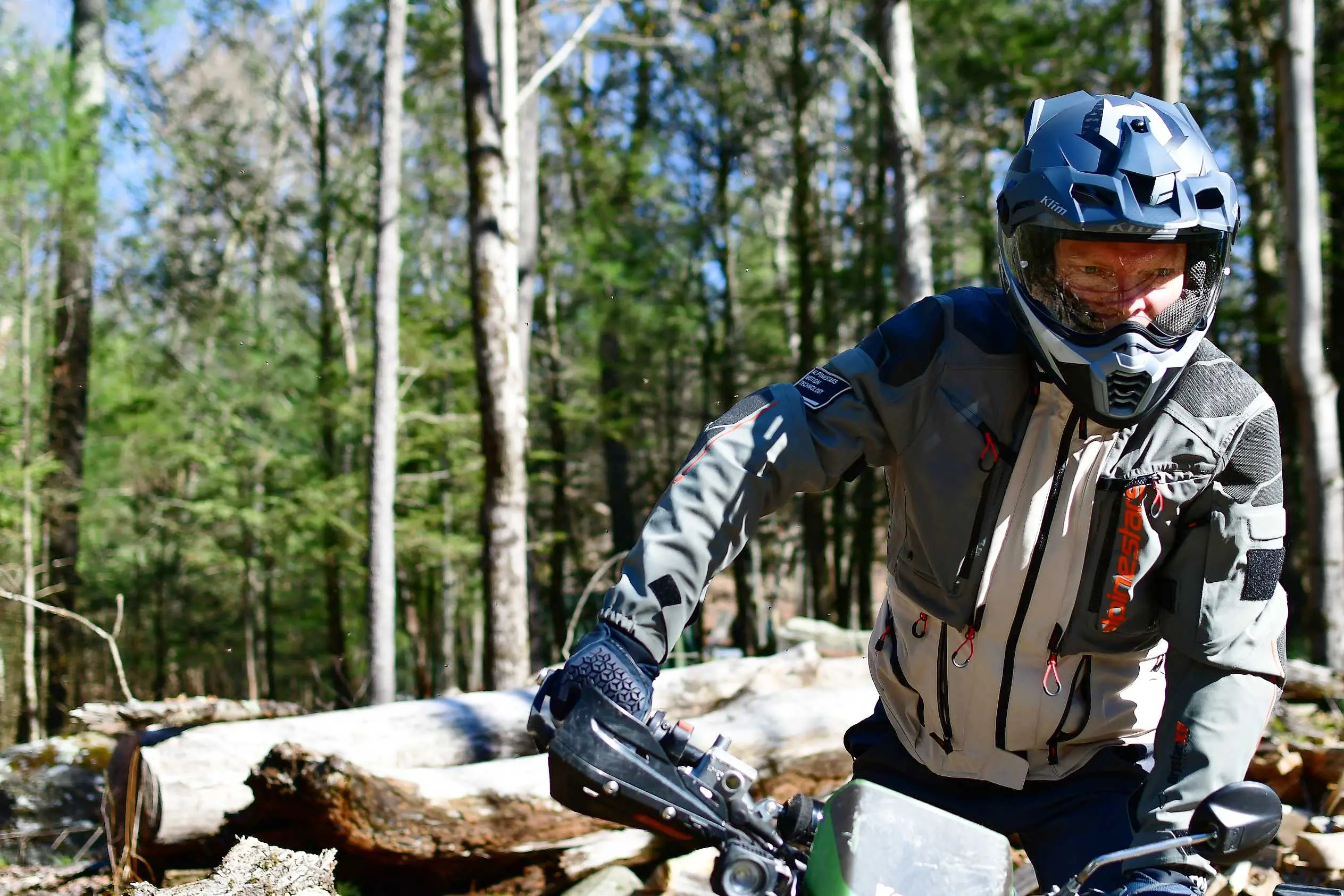 man standing in footpegs of adventure motorcycle bike in forest 