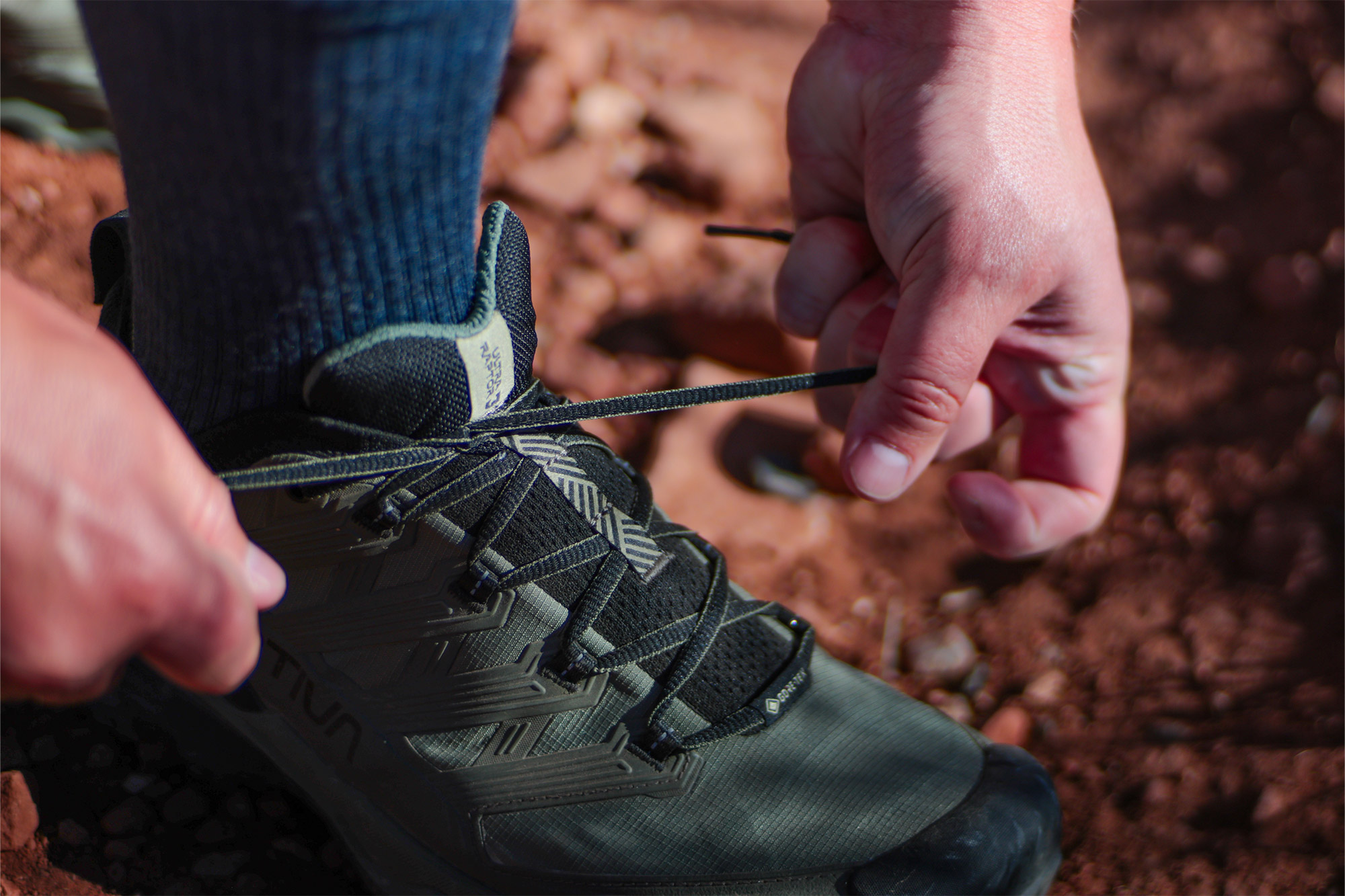 Hands tightening laces on a trail running shoe during use
