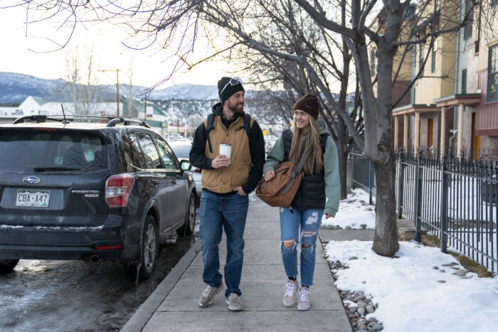 two gearjunkie testers wearing laptop packs walk on a snowy sidewalk in colorado