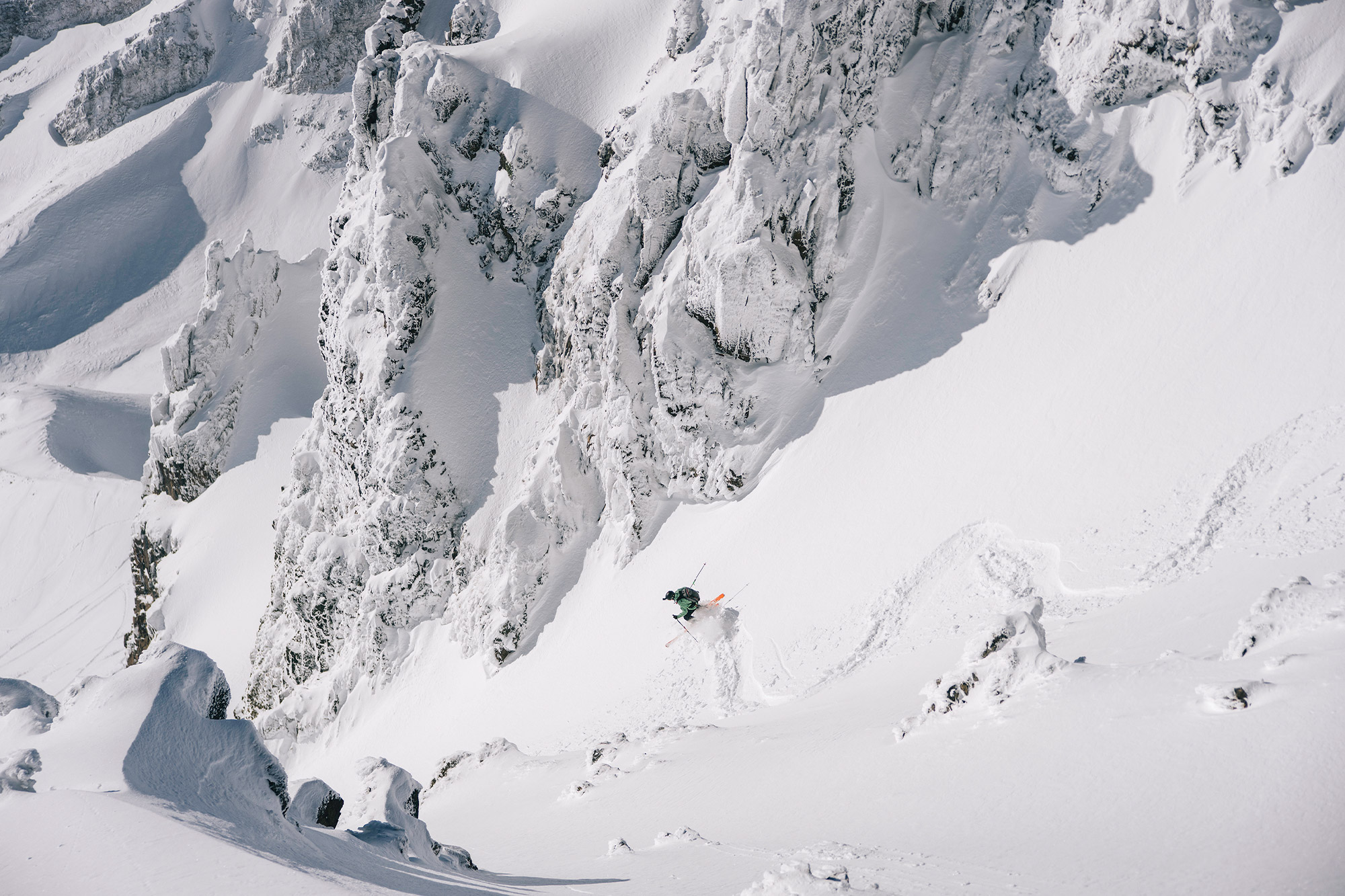 Skier descending steep terrain in firm spring snow conditions
