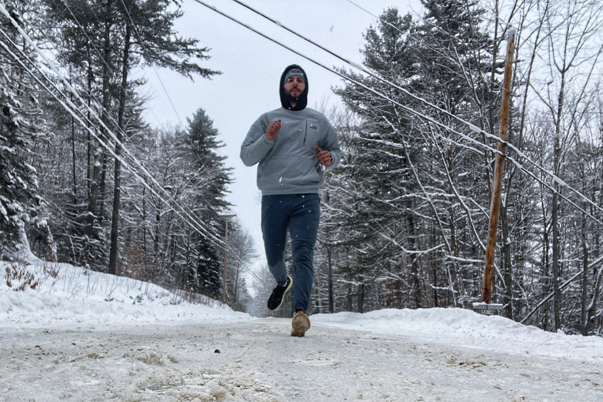 Runner wearing Tracksmith Eliot NDO shoes jogging along a snowy road