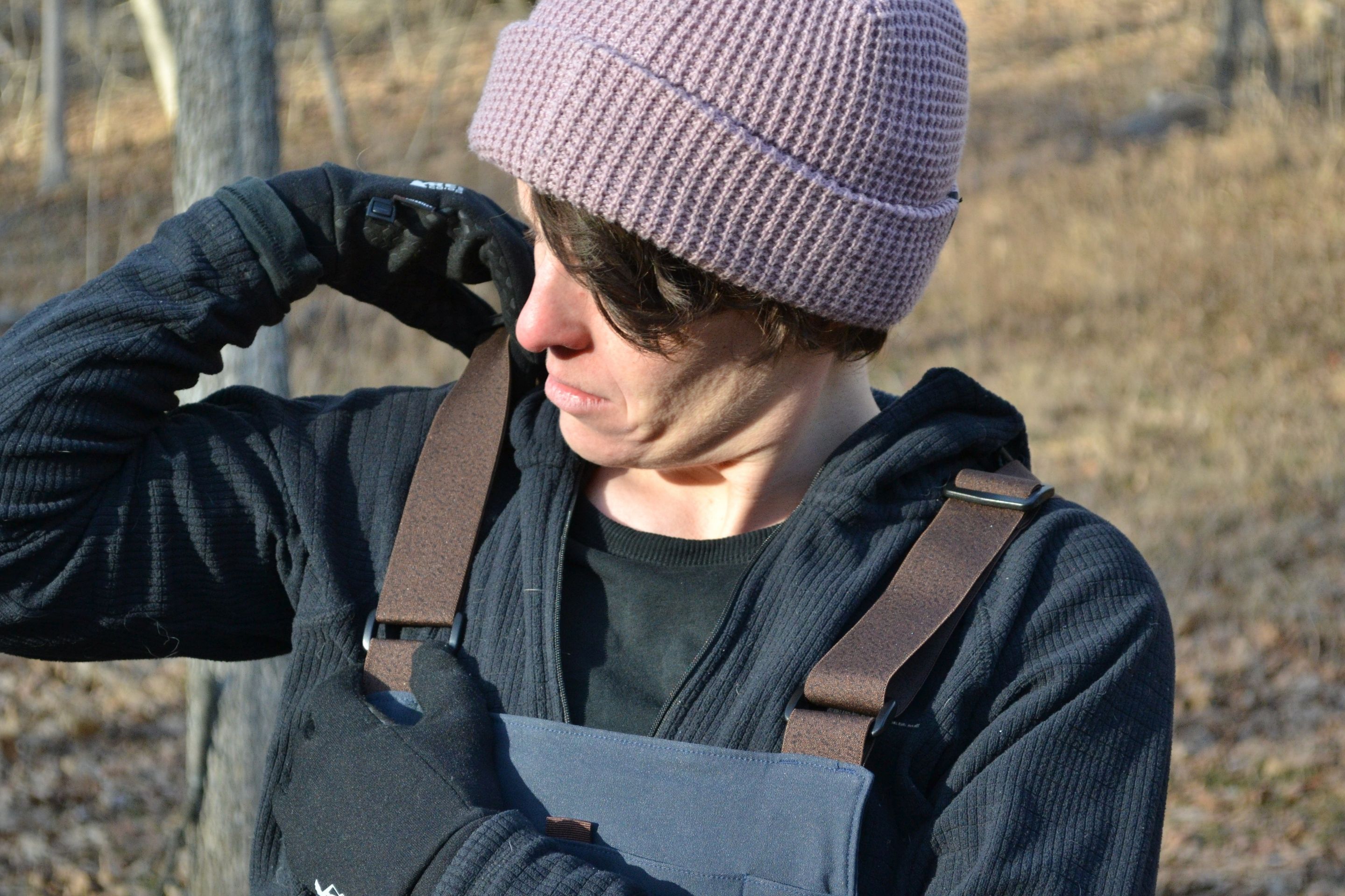 person adjusting straps on overalls
