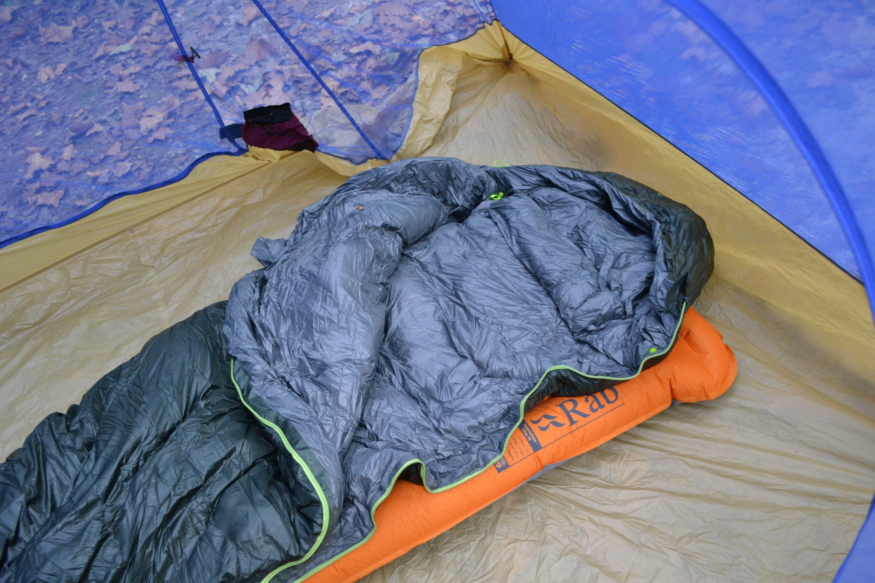 sleeping bag zipped open laid out on sleeping pad