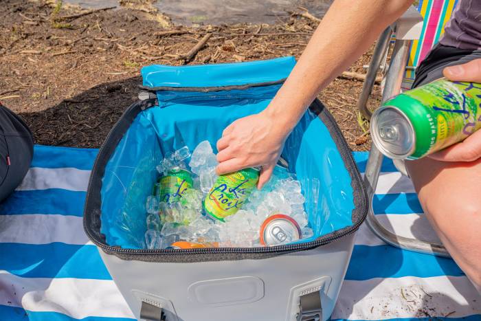 hand adding cans to soft cooler