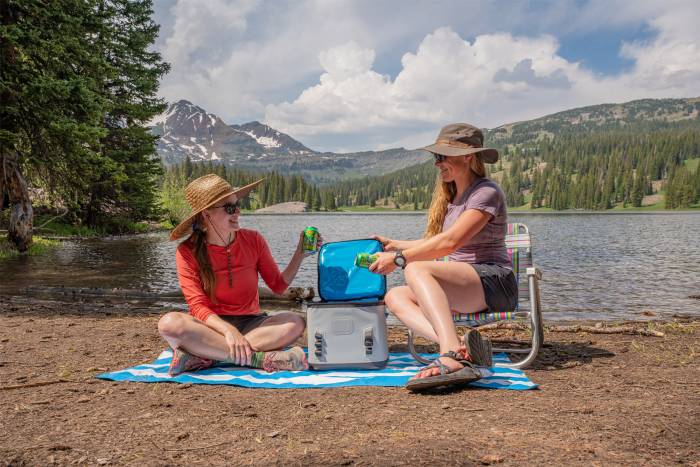 two women sitting next to lake with soft cooler 