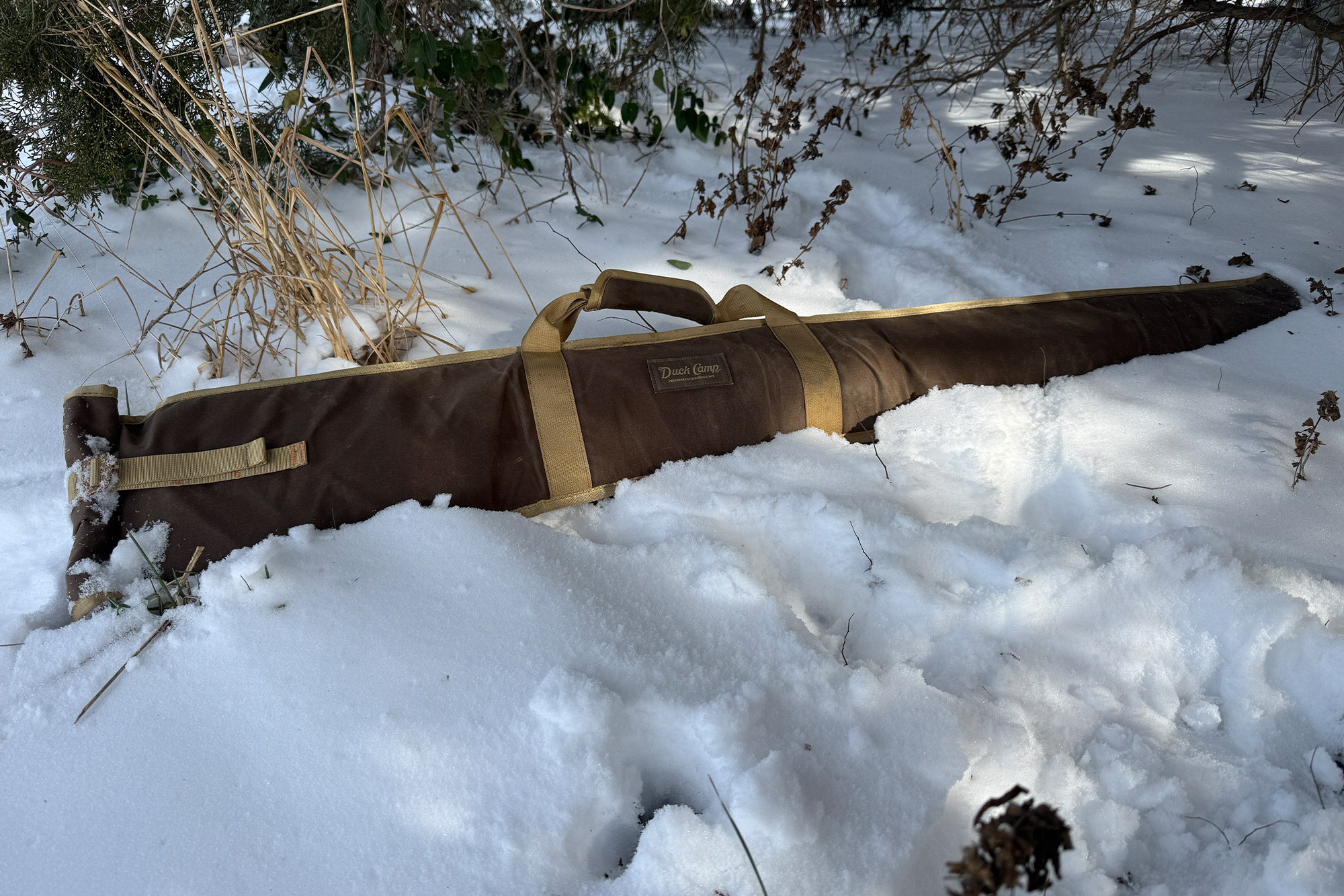 Canvas gun sleeve placed in snow with straps visible