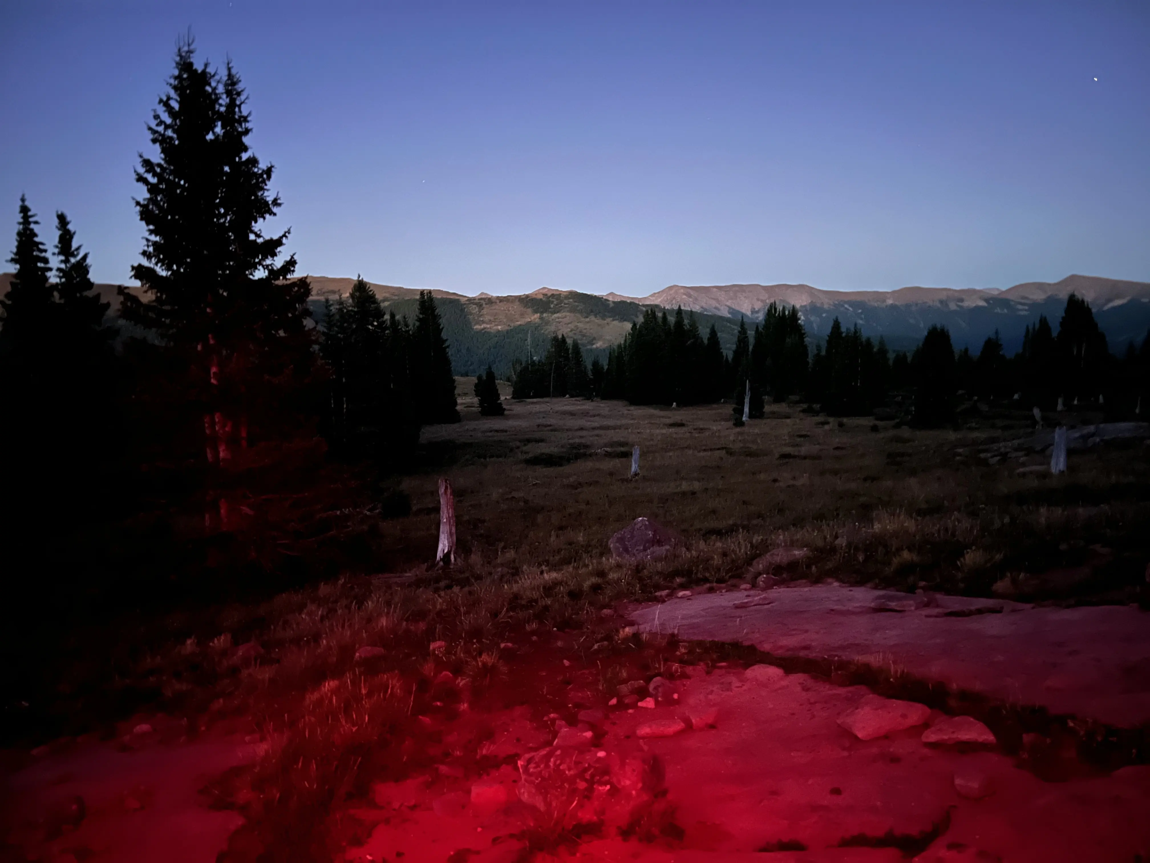 Red light of headlamp in mountains at dusk