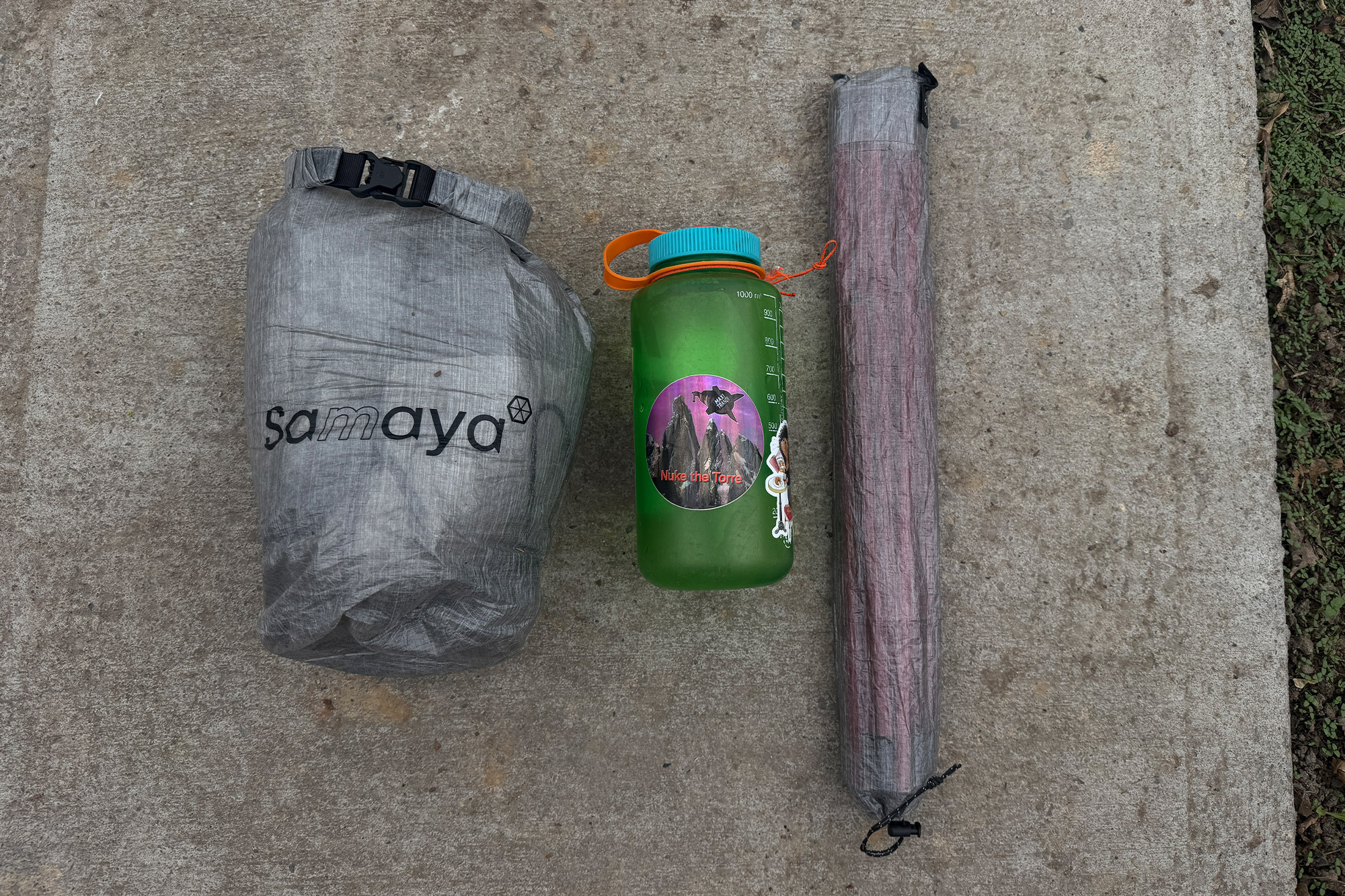 Packed Samaya tent next to a water bottle and pole bag for size reference