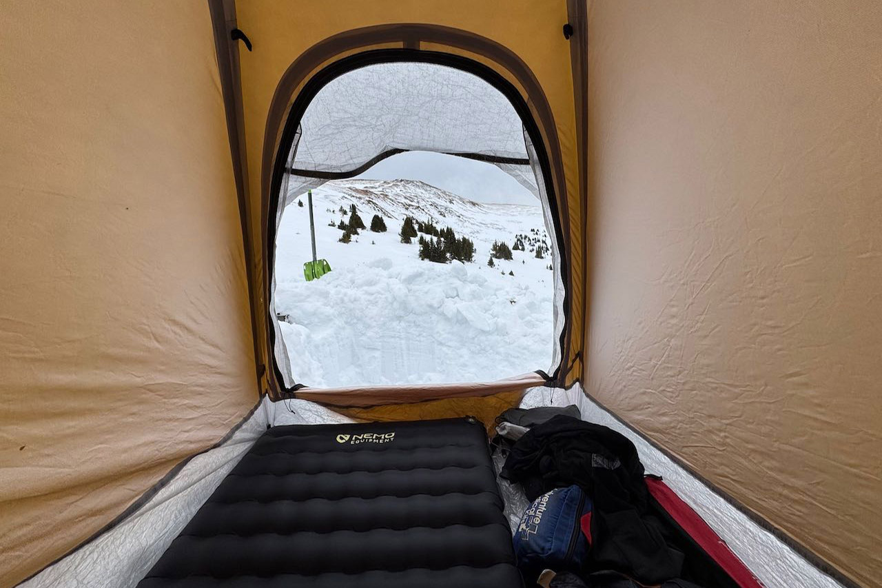 View from inside tent looking out through open door to snowy landscape