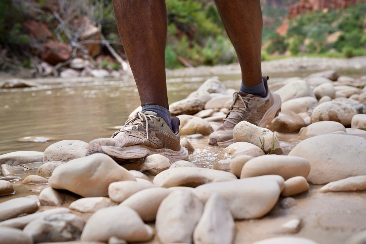 A man walks by a river with hiking shoes