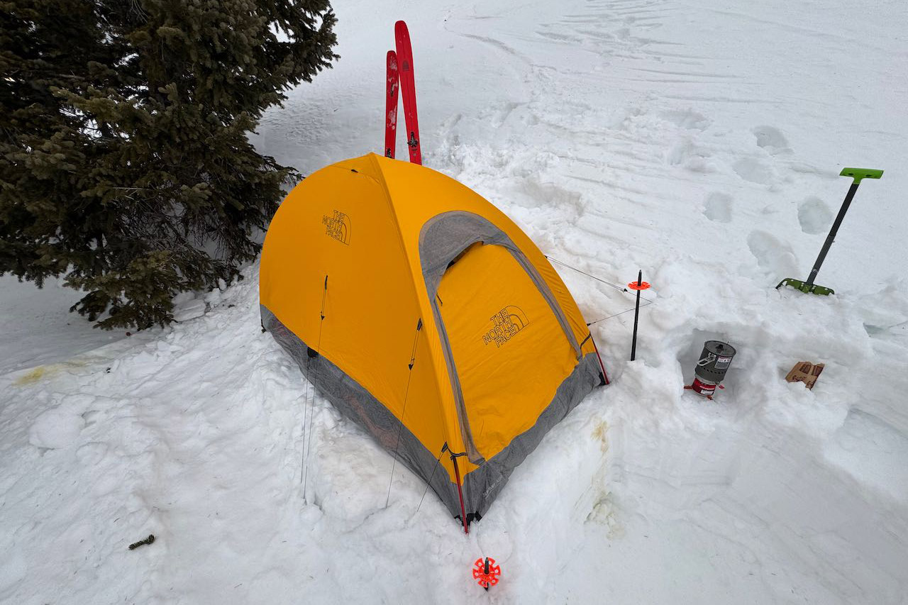 The North Face Assault 2 AMK tent set up in snow with skis and stove nearby