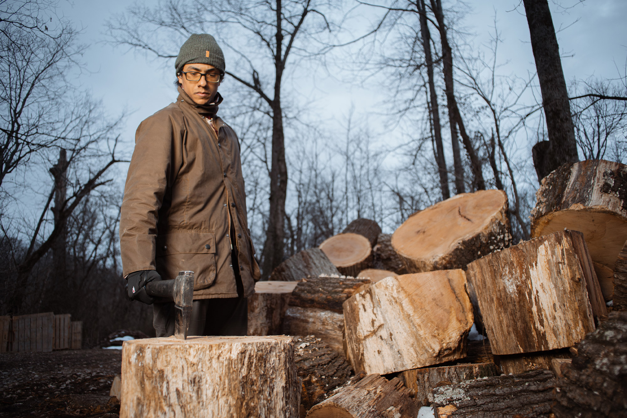 A person chopping wood while wearing the Barbour Beaufort Wax Jacket