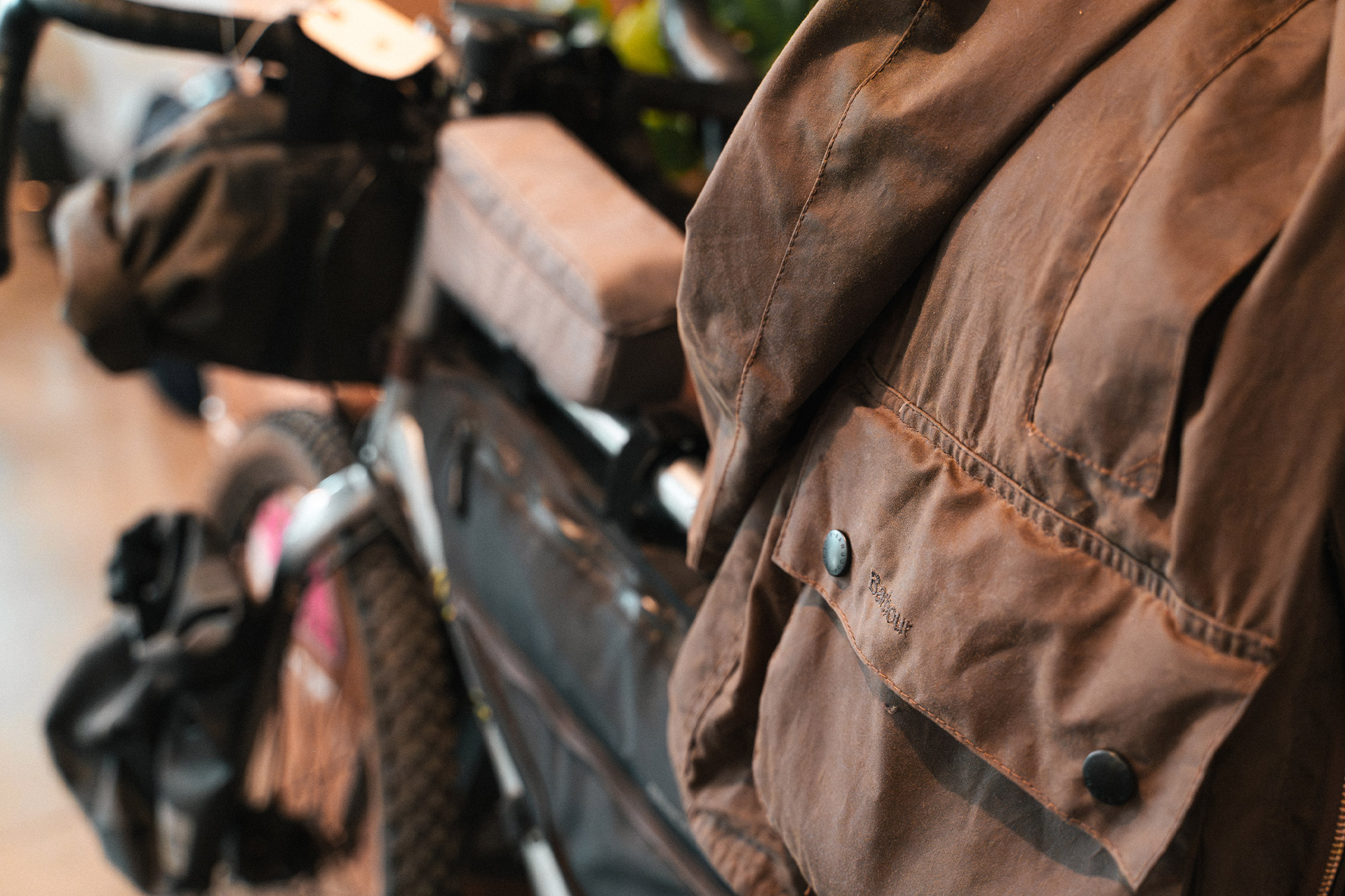 Detail of the Barbour Beaufort Wax Jacket pocket and snap closure near a bicycle